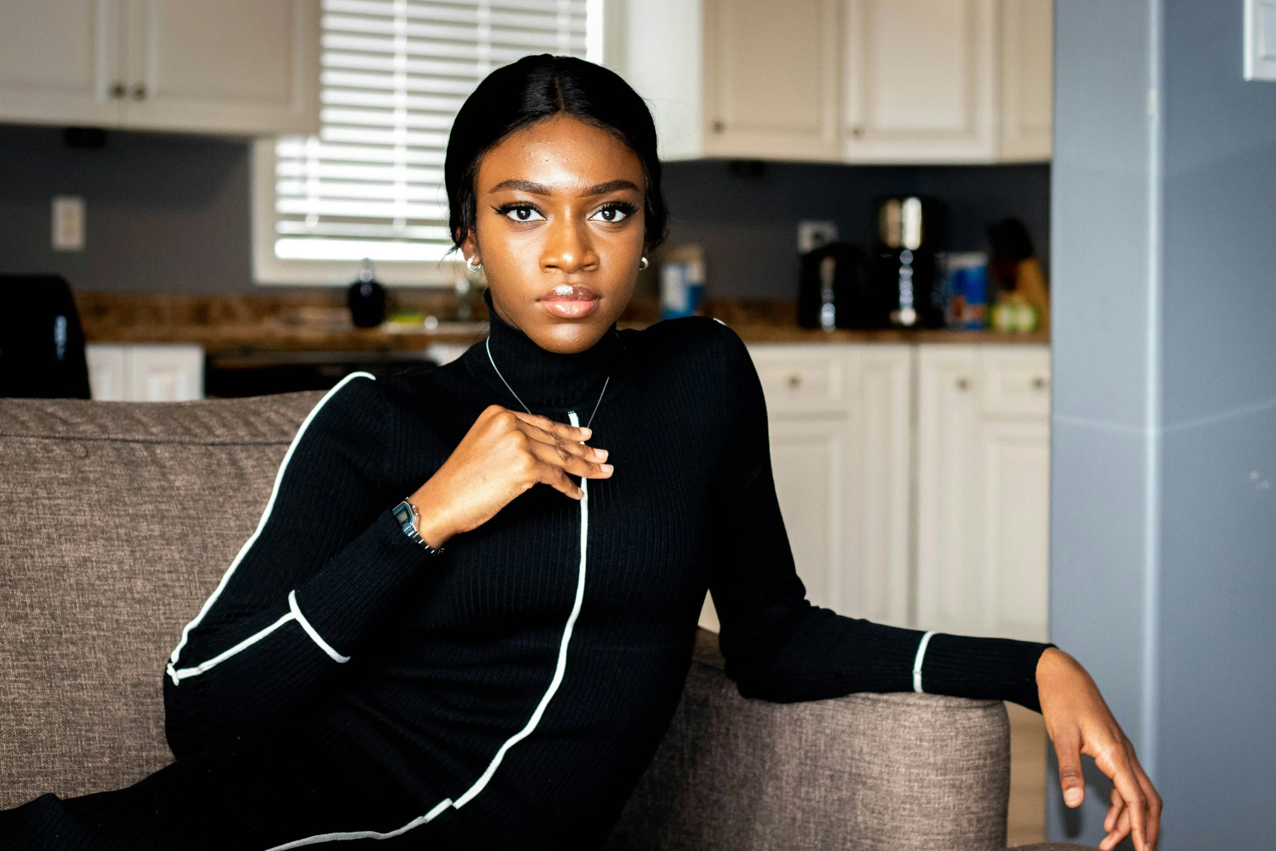 Black woman sits on a couch and stares directly into camera