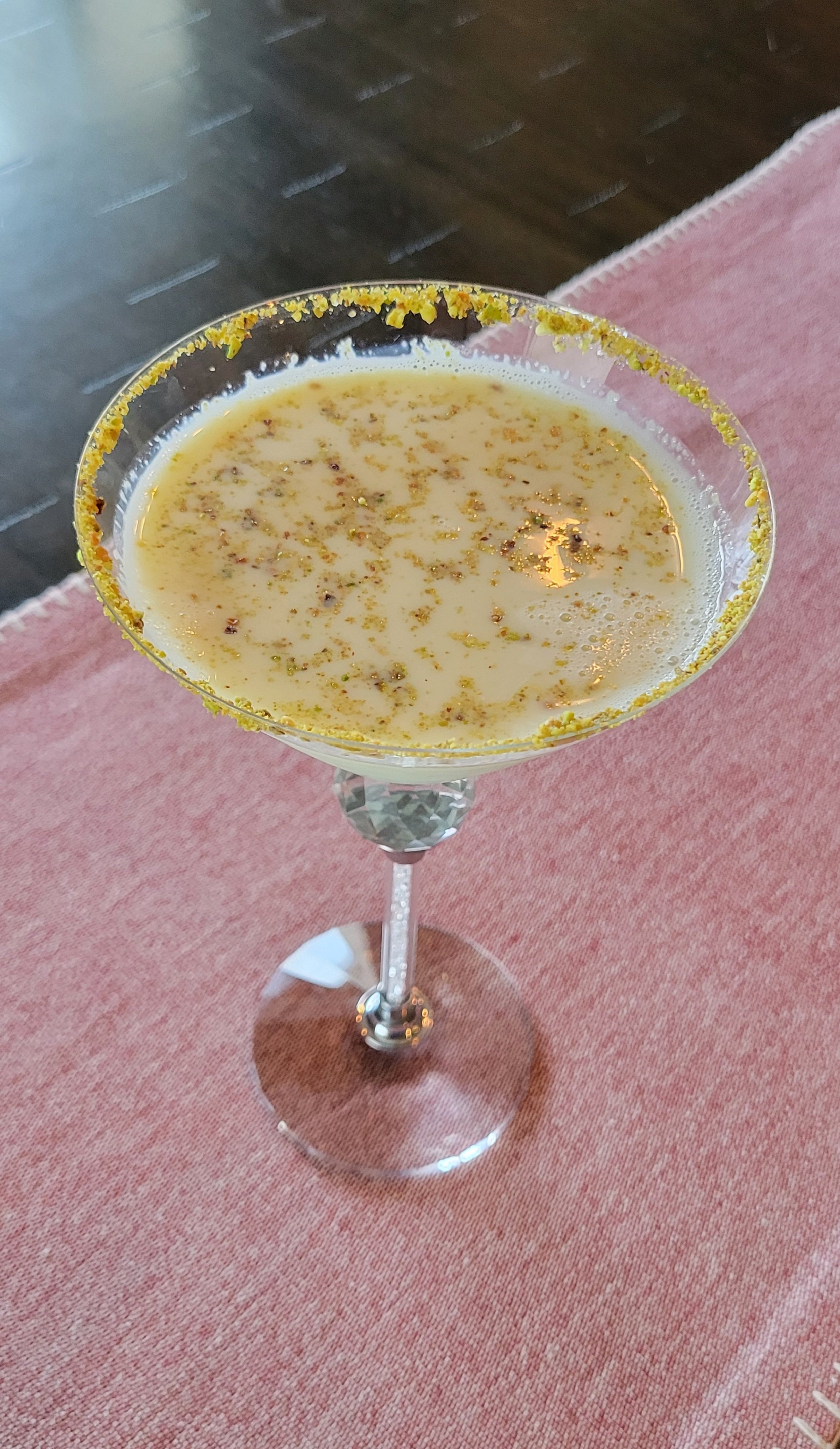 Close-up of a cocktail glass with a salted rim, filled with a creamy, frothy beverage garnished with spices.