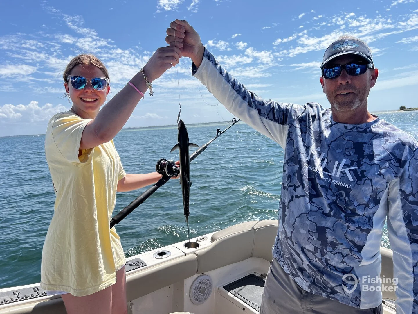 Girl on a boat holding up a fish she caught in the Gulf with Captain Steve and Bluewater Charter