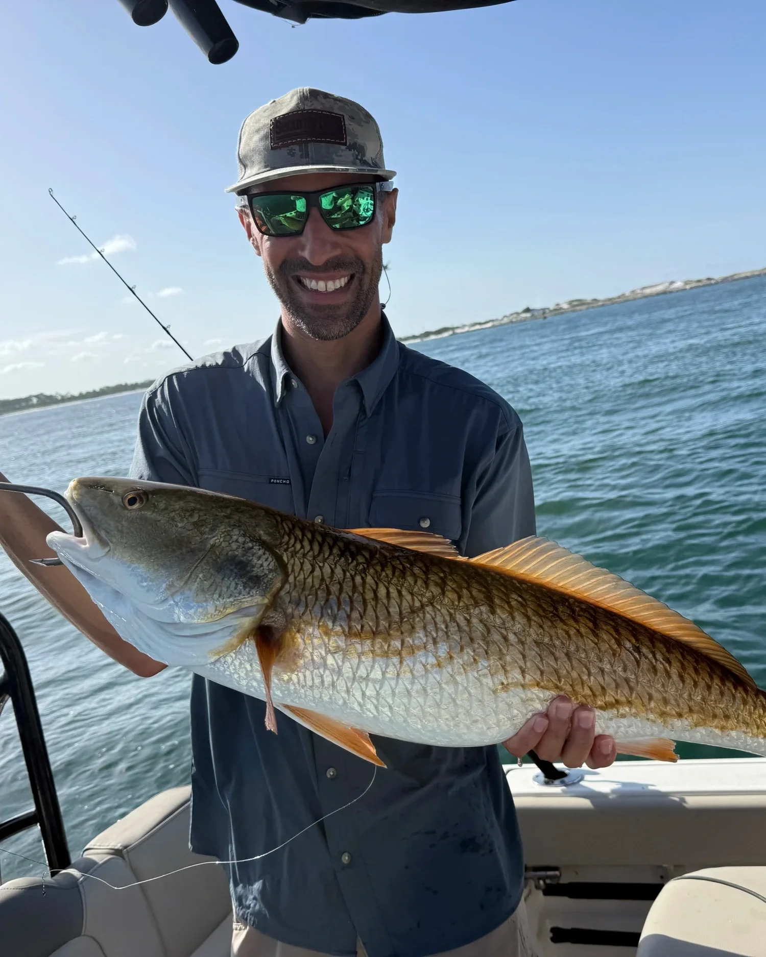 Guest proudly holding a redfish caught during an inshore fishing charter on Florida’s Emerald Coast