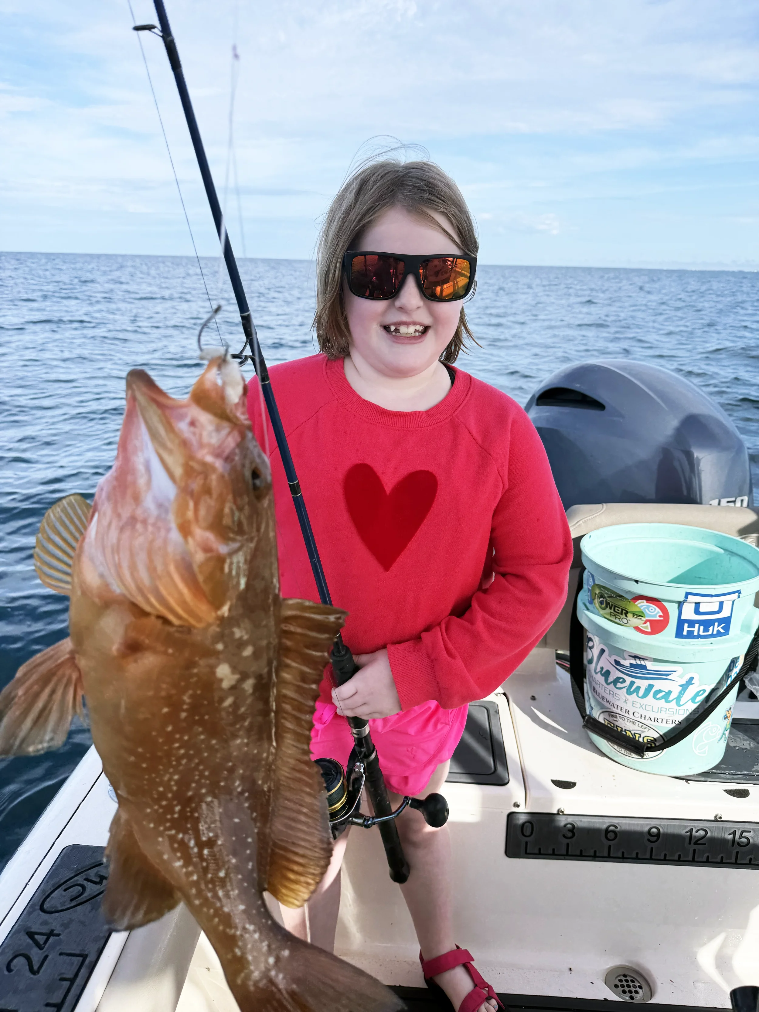 Girl holds up a red grouper she caught along the Emerald Coast