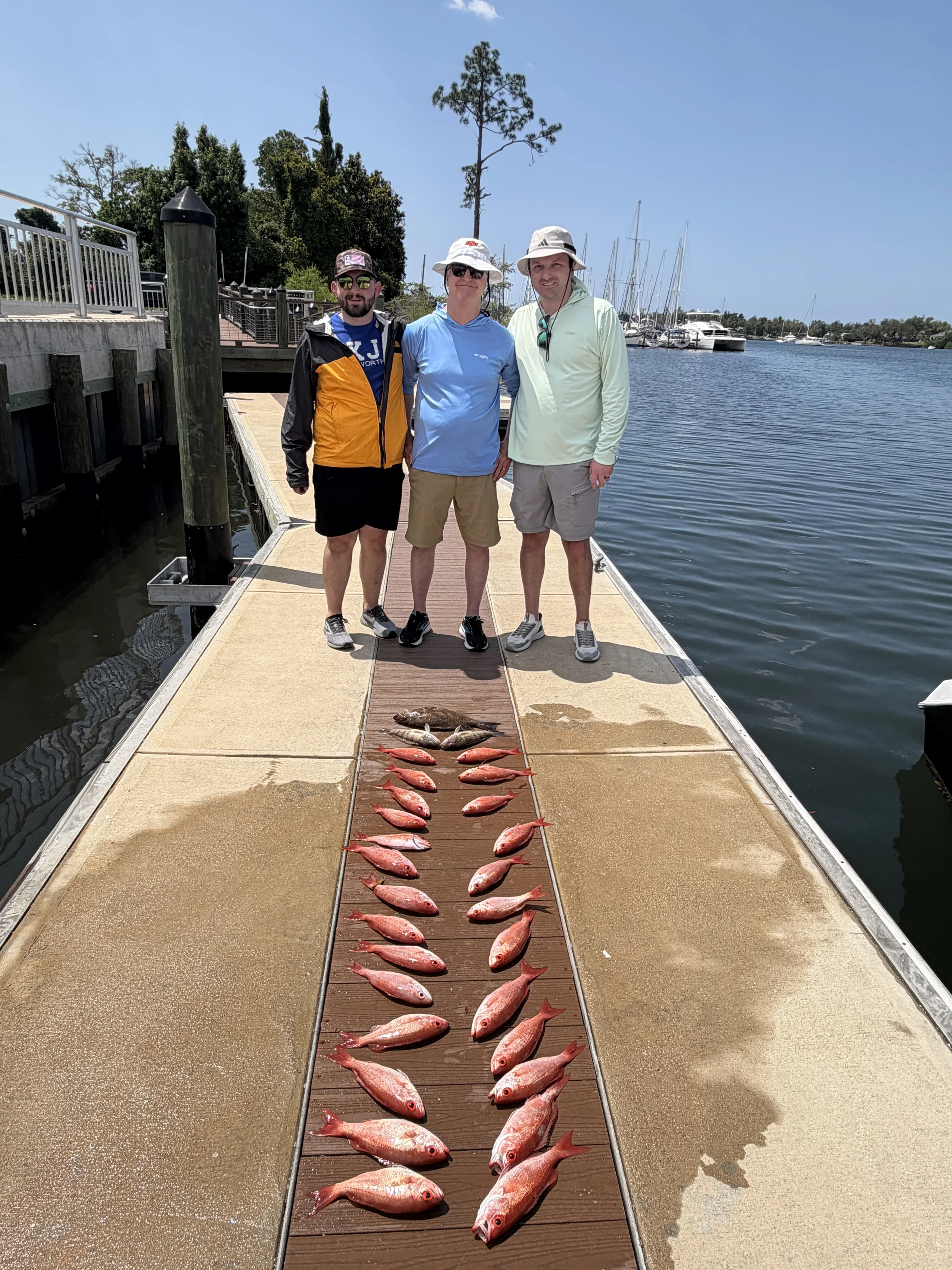 Group of men standing on a dock with the snapper they caught in the Gulf with Bluewater Charter