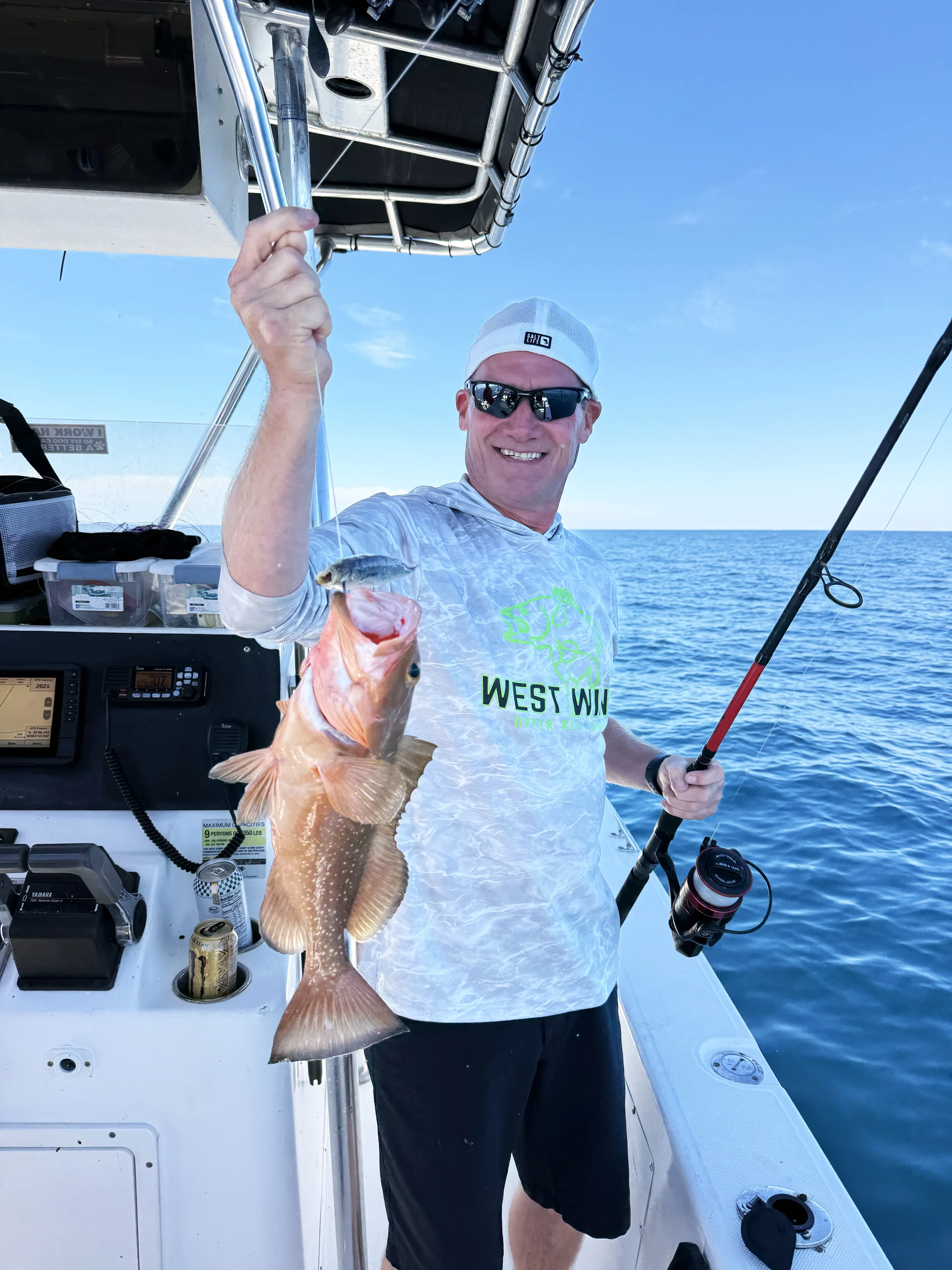 A man holds a red grouper toward the camera after catching it on Bluewater Charter in the Gulf