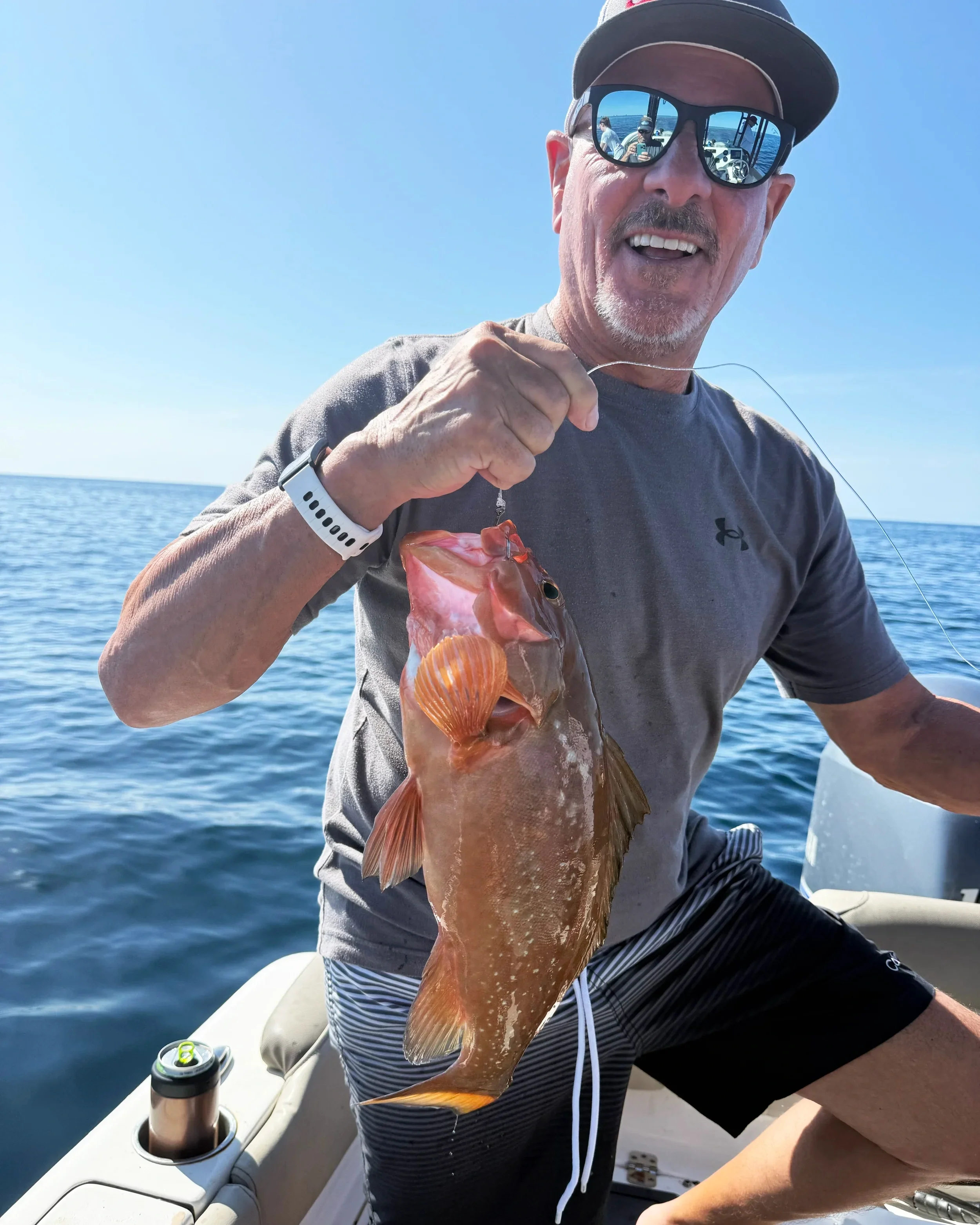 Angler holding a red grouper caught on an offshore fishing charter near 30A and Destin Florida