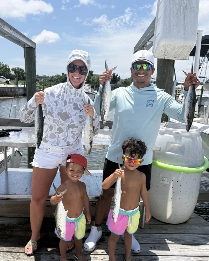 Family celebrating a successful fishing trip with Spanish mackerel caught on Florida’s Emerald Coast