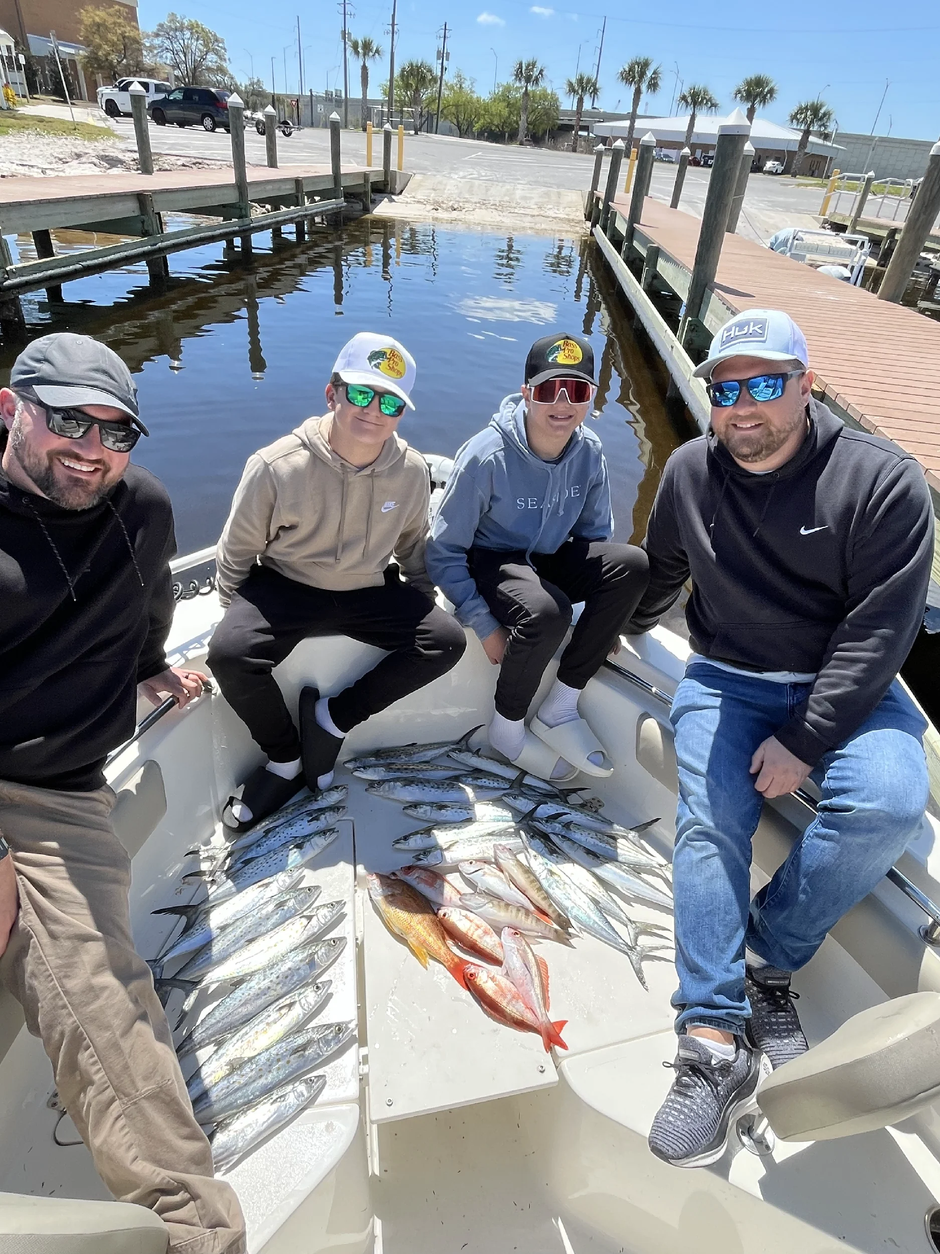 Two men and two teen boys on Bluewater Charter in a Gulf harbor after a day of fishing