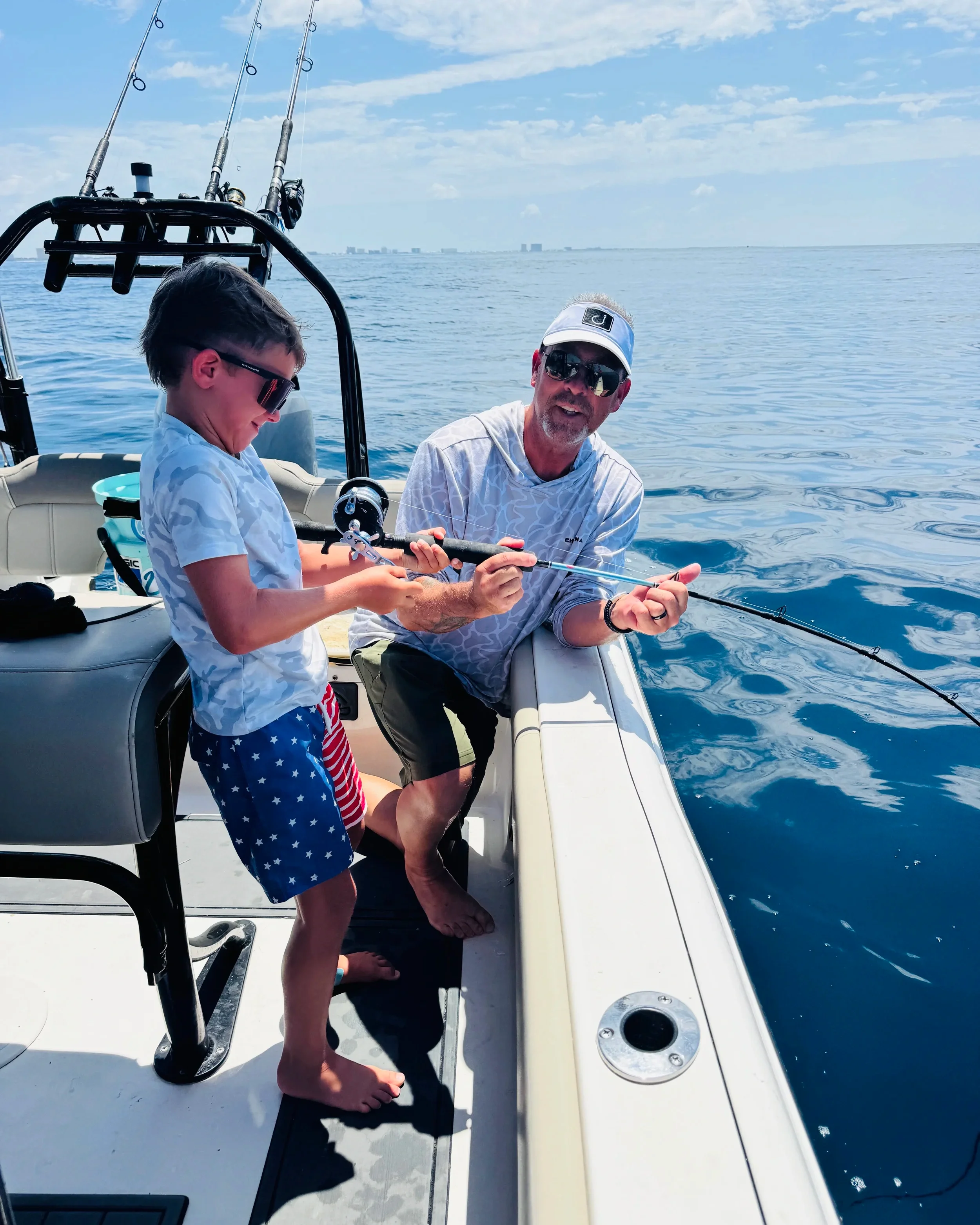 Captain Steve helping a young angler reel in a fish during a family fishing charter on Florida’s Emerald Coast