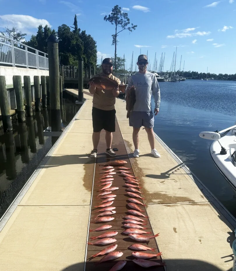 Two men hold up the fish they caught with Bluewater Charter along the Emerald Coast
