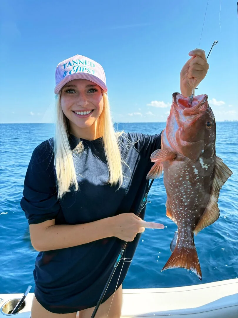 Young woman shows off her red grouper caught with Bluewater Charter near 30A and Destin