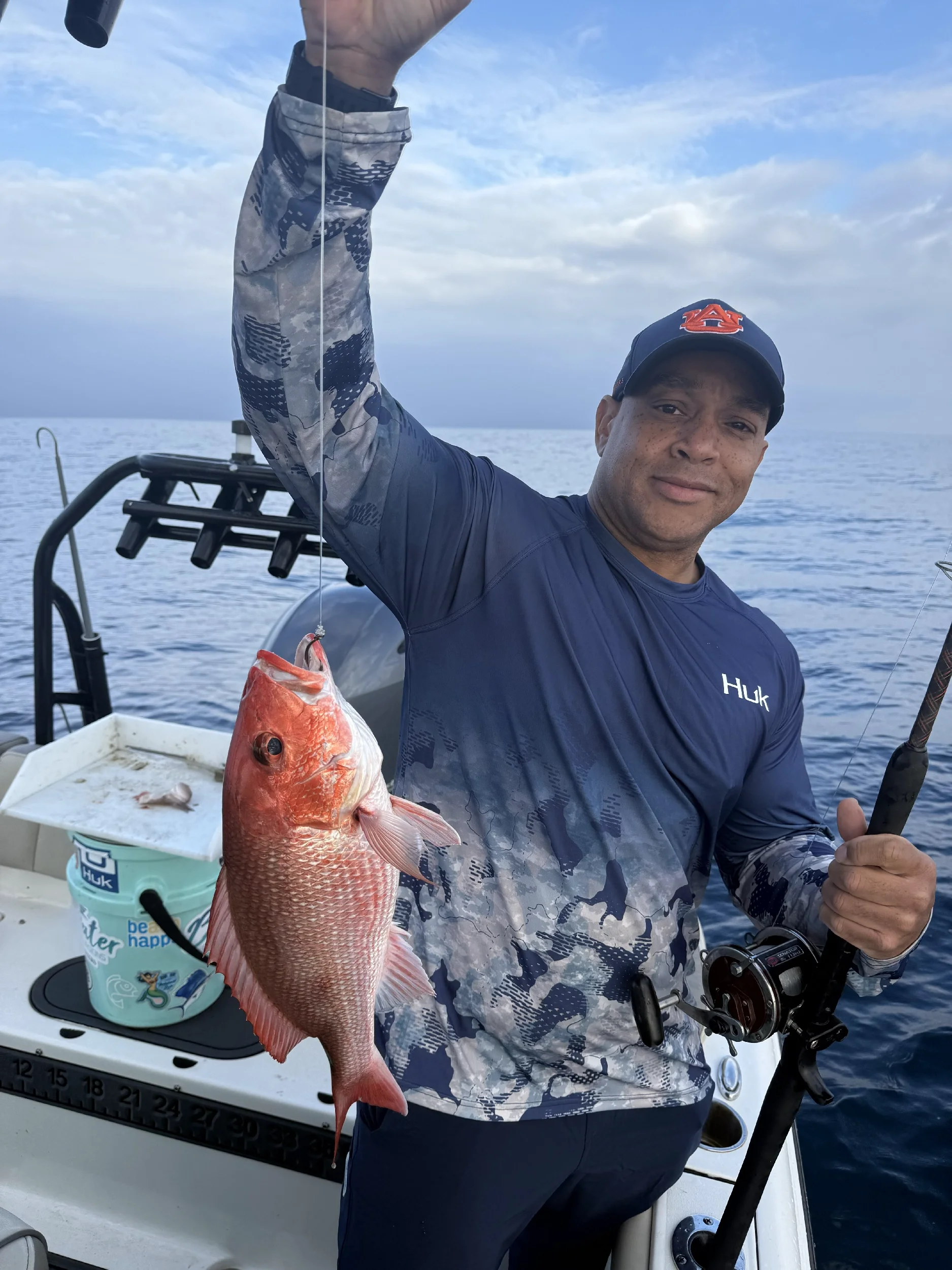 Man holding up his Gulf caught Snapper on a boat