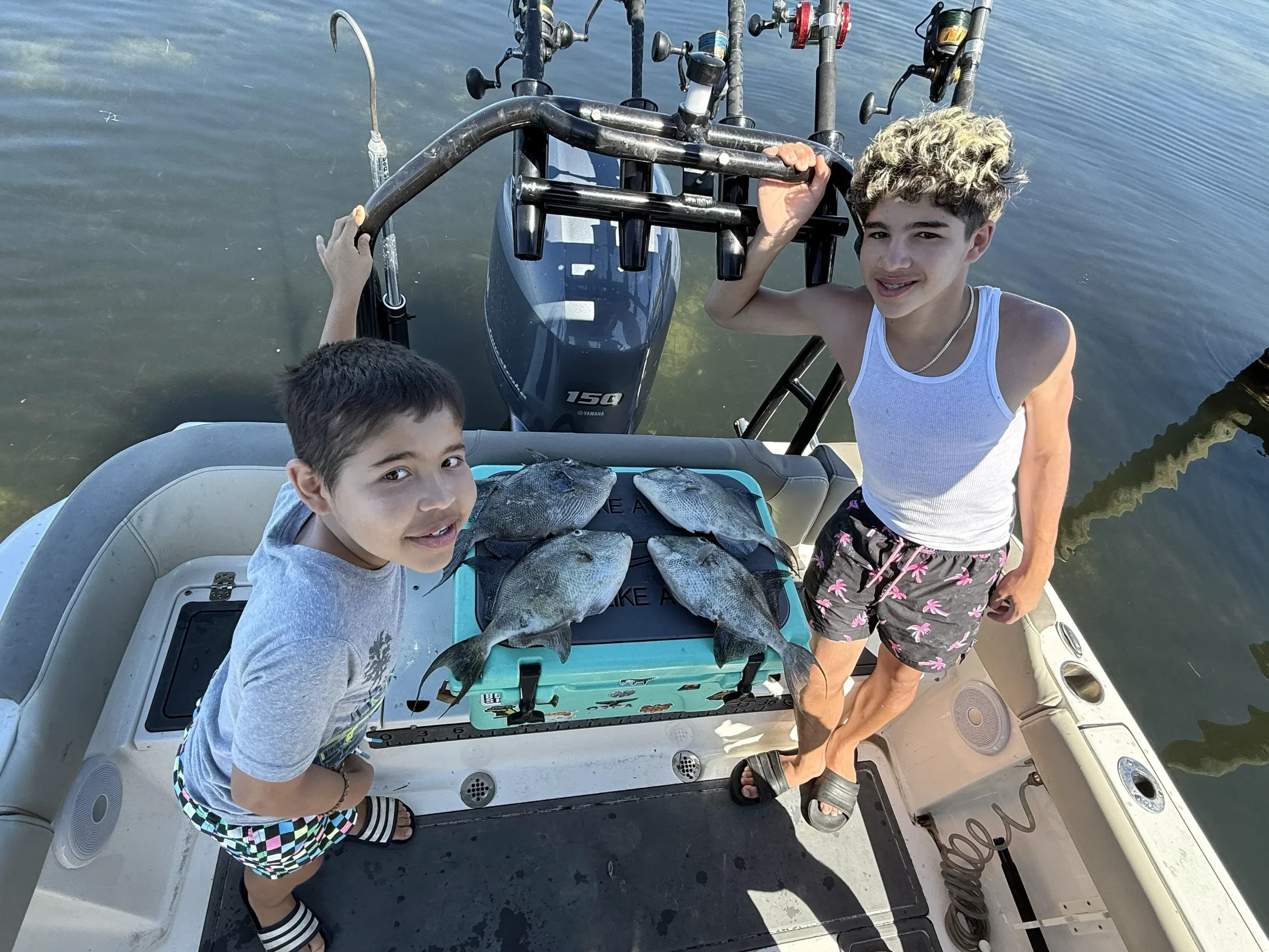 Two kids showing off the fish they caught in the Gulf