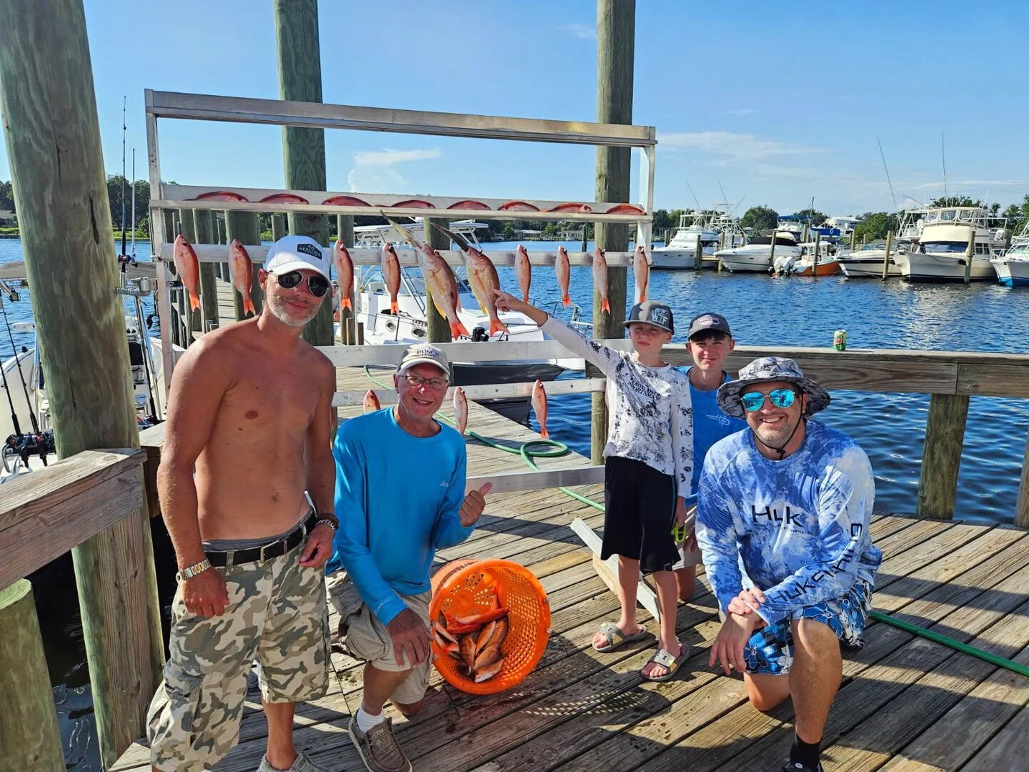 Family and friends celebrating a successful Bluewater Charter trip with a catch of snapper at the dock