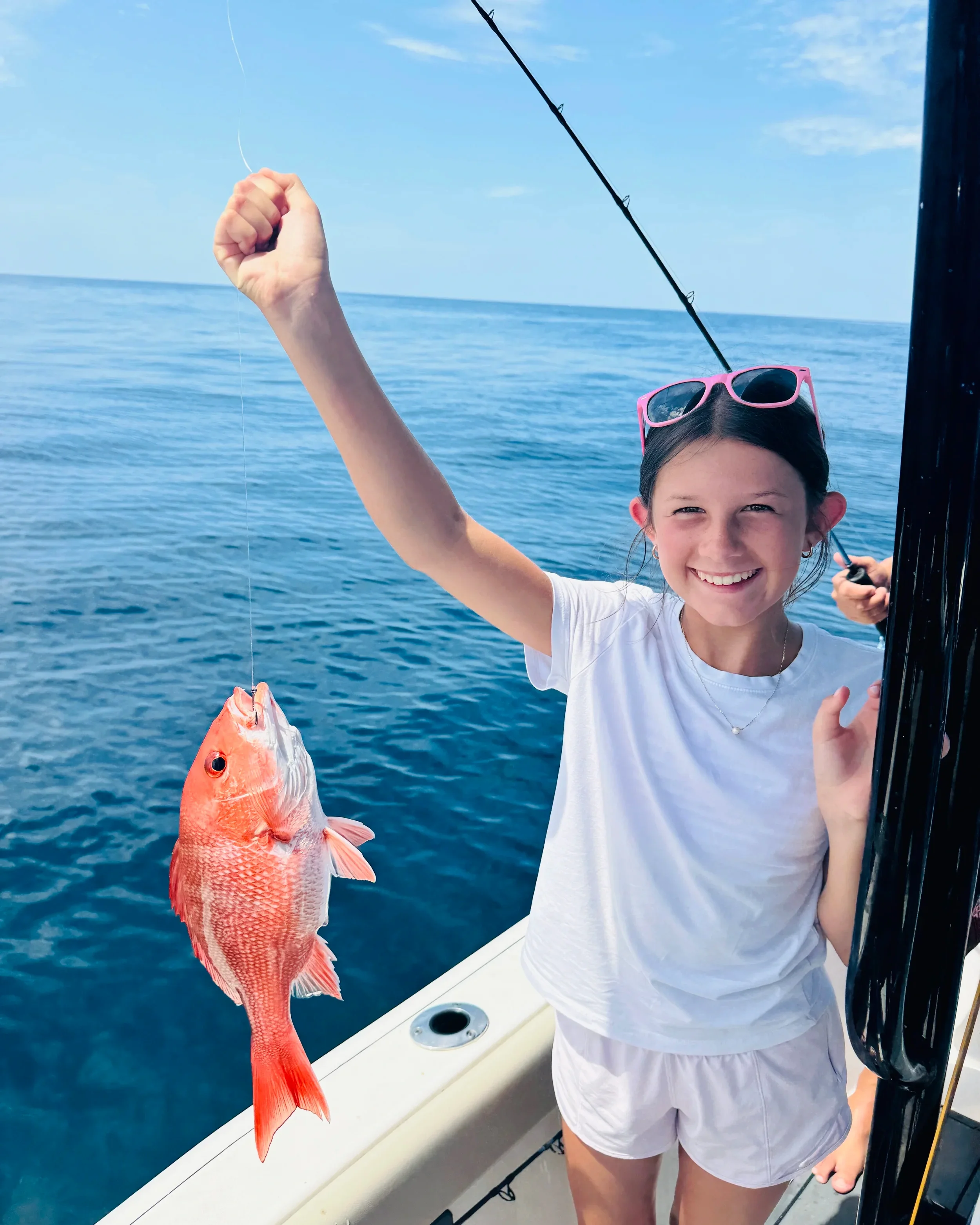 Young angler proudly holding a freshly caught snapper during a family fishing charter in Panama City Beach.