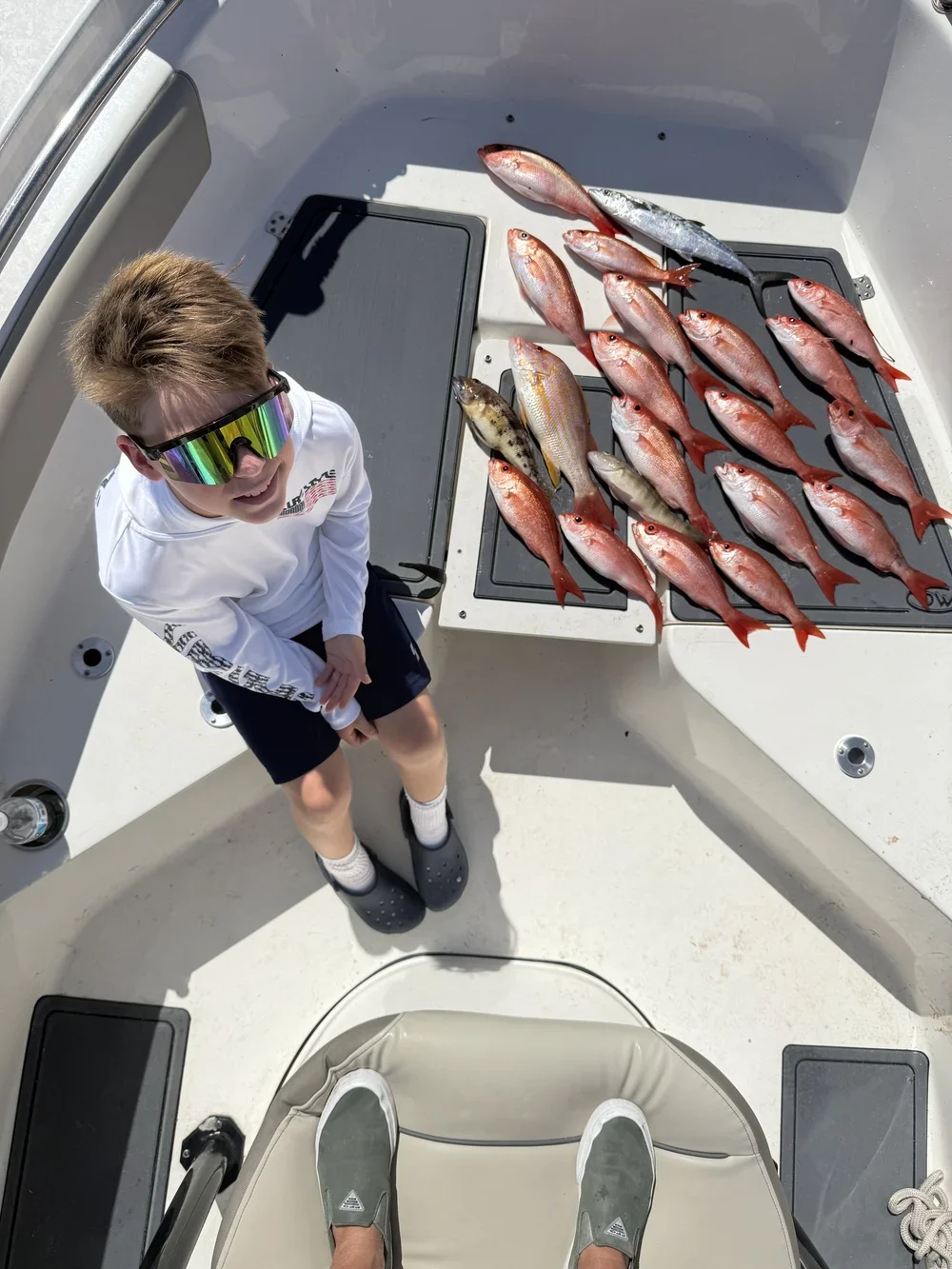 Young boy on fishing boat with Snapper caught next to him
