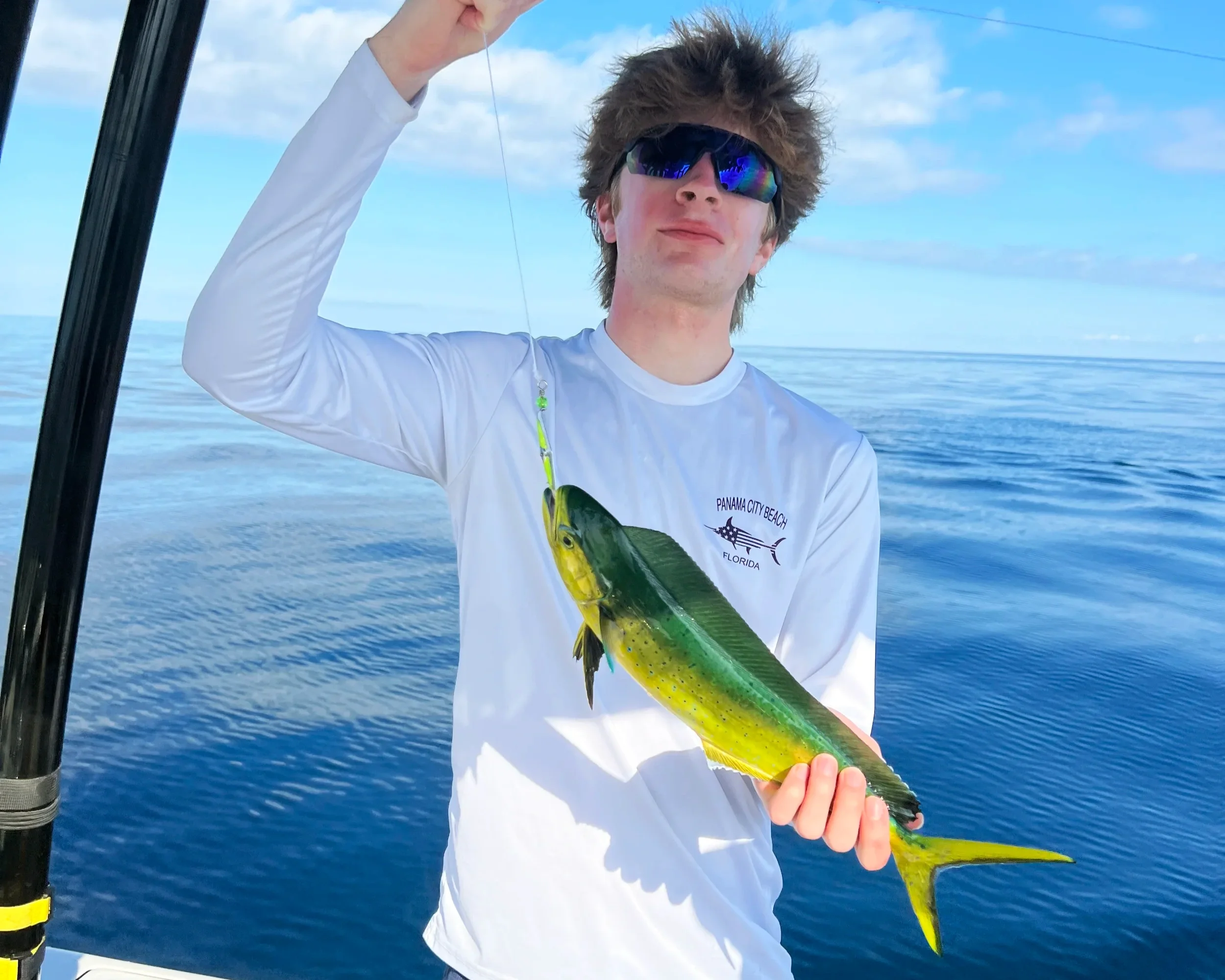 A young man holds up a Mahi Mahi he caught along the shores of Panama City Beach