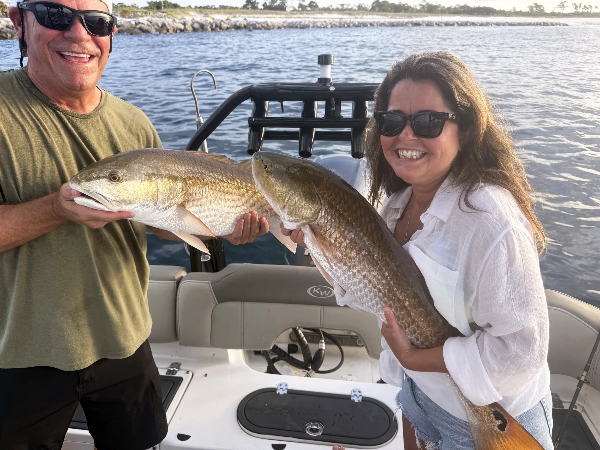 Couple showing off redfish caught during a family-friendly inshore fishing charter on Florida's Emerald Coast