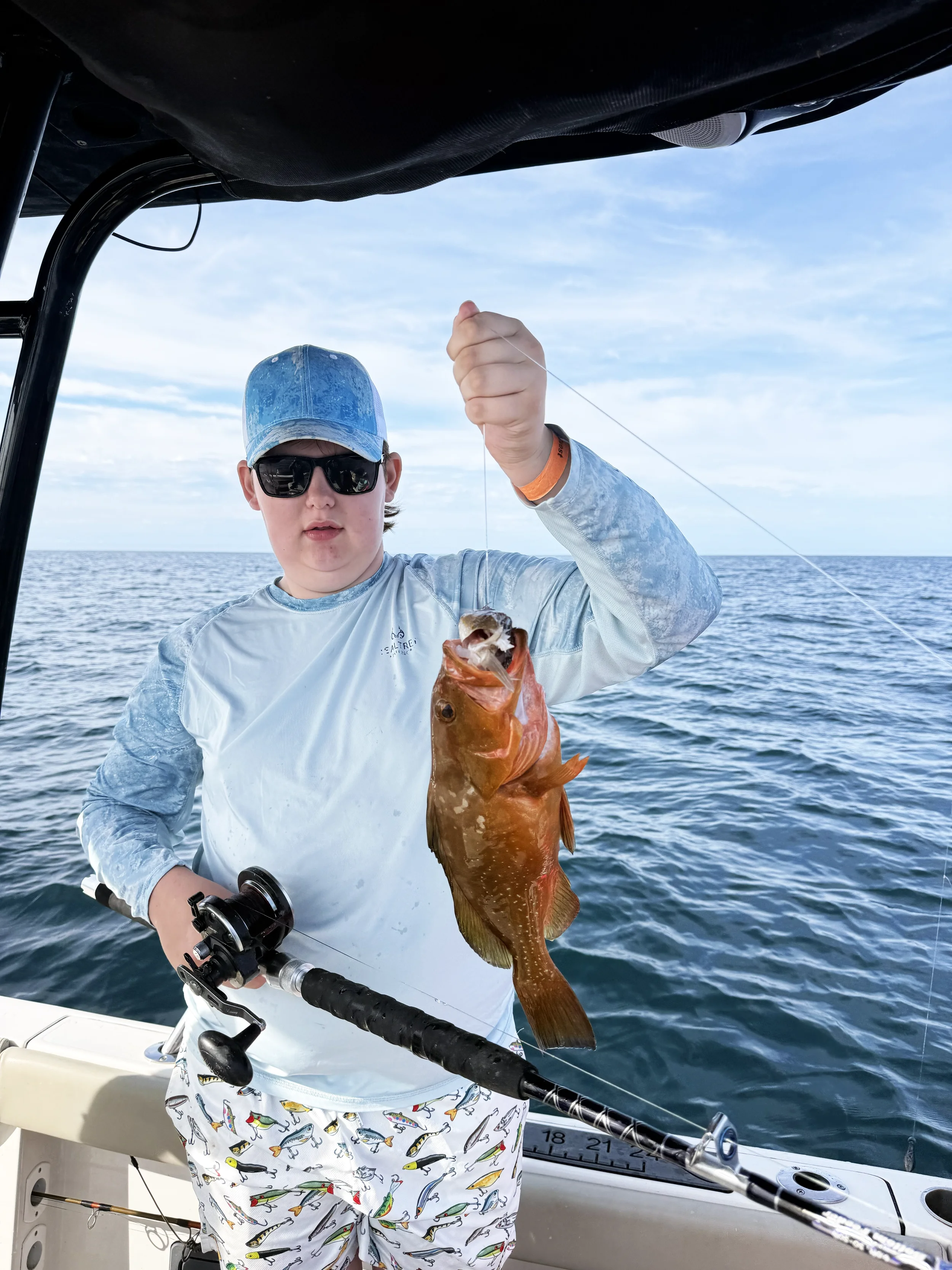 A young boy holds up a grouper he caught in the Gulf of Mexico