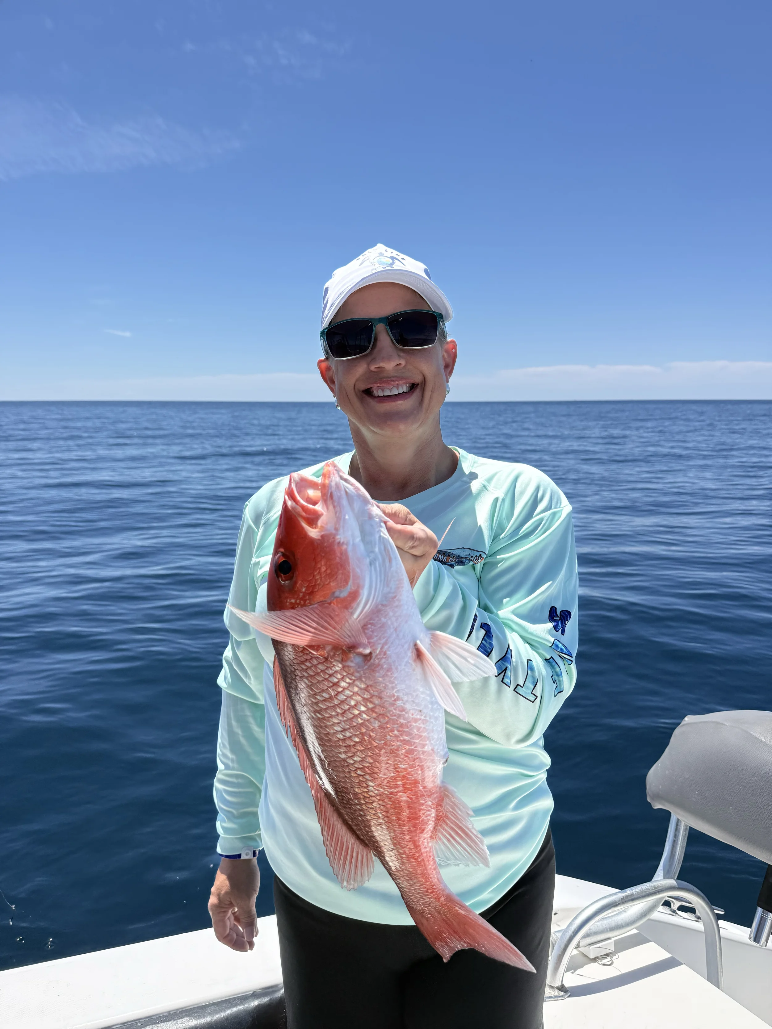 A woman smiles as she holds up a vermilion snapper she caught along Florida's Gulf Coast