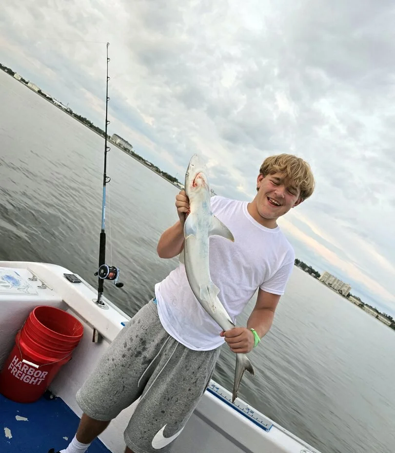A young boys holds up a small shark he caught along the Gulf Coast of Florida