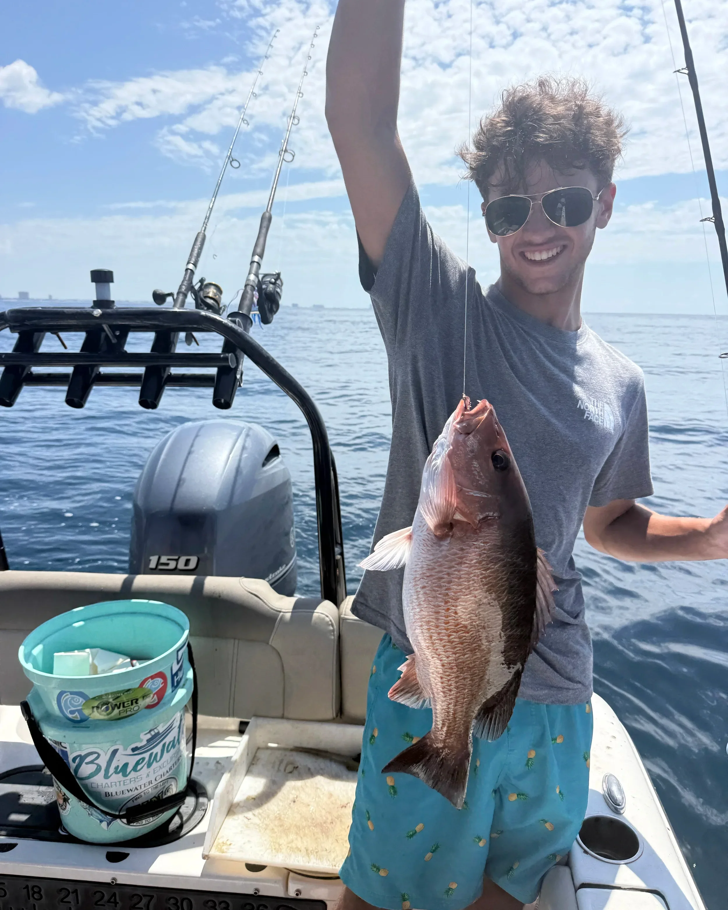Young angler proudly holding a mangrove snapper caught during a Bluewater Charter fishing trip on Florida’s Emerald Coast