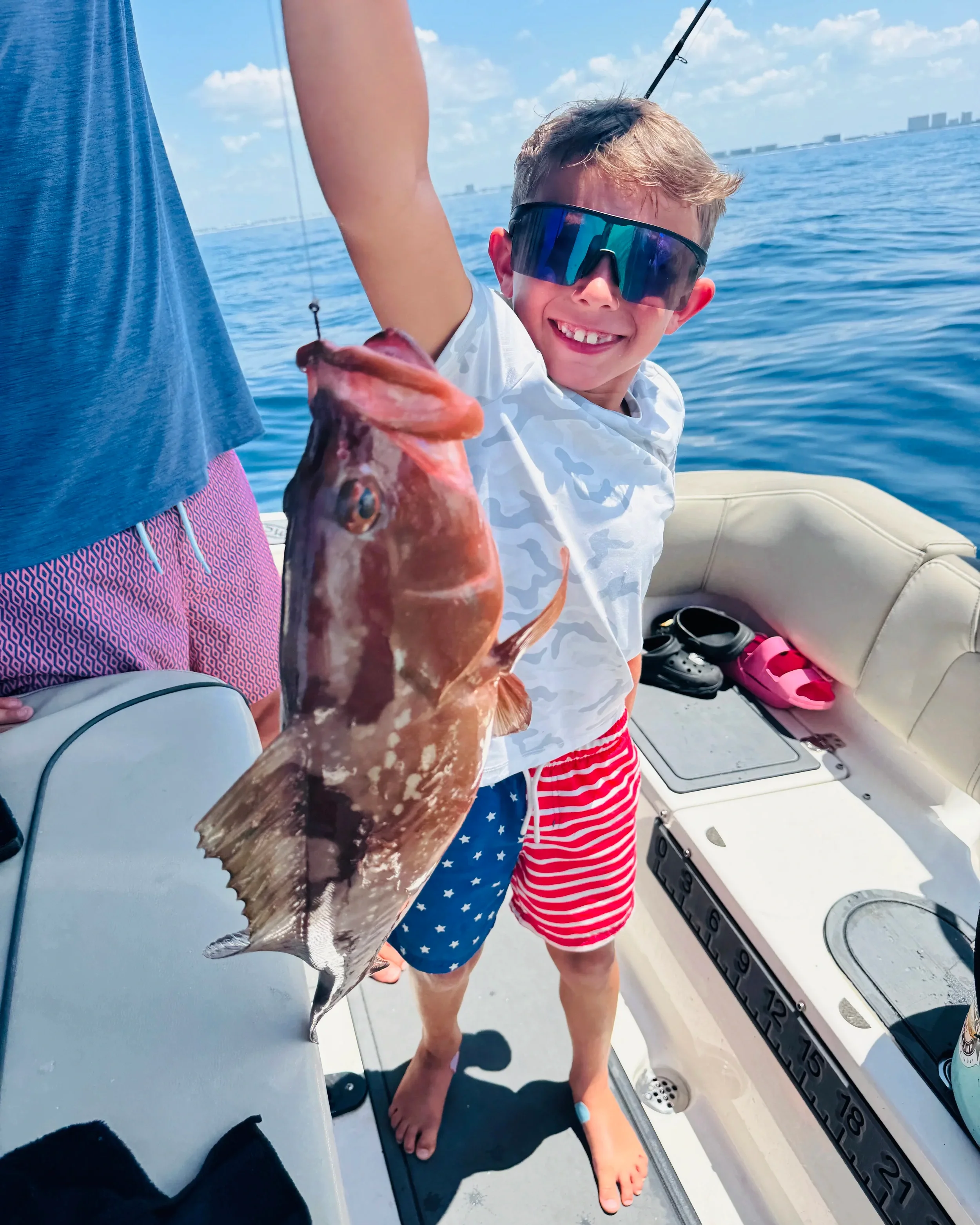 Young angler proudly holding a red grouper caught during an offshore fishing charter on Florida's Emerald Coast