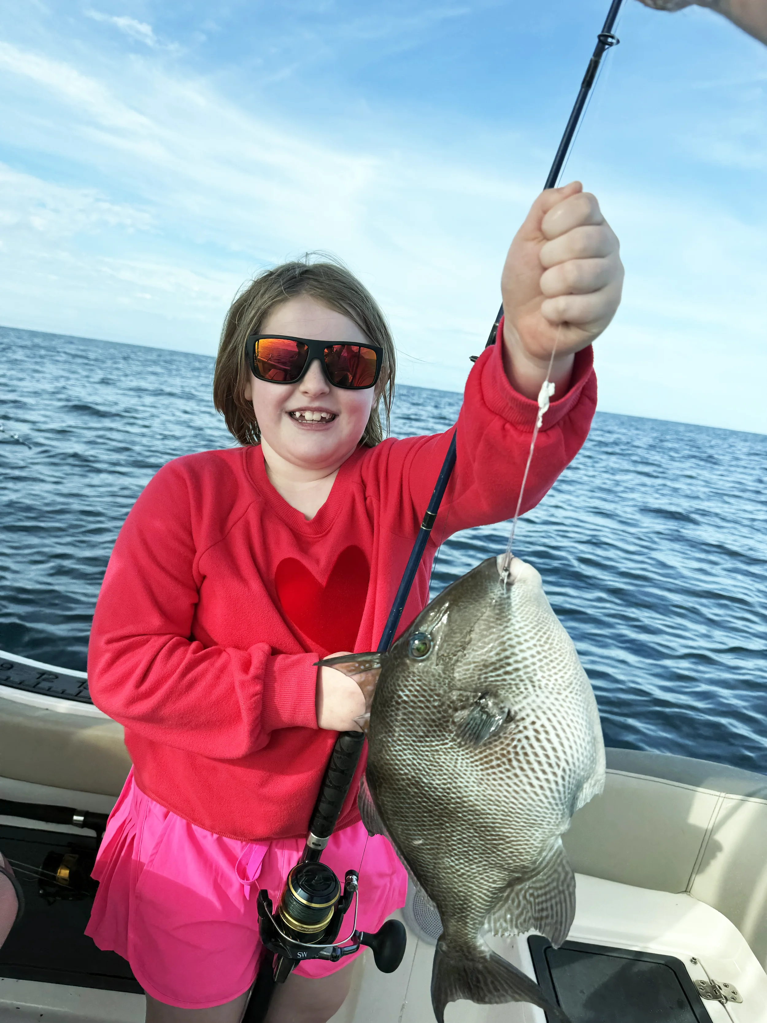 A young girl holds up a triggerfish she caught in the Gulf