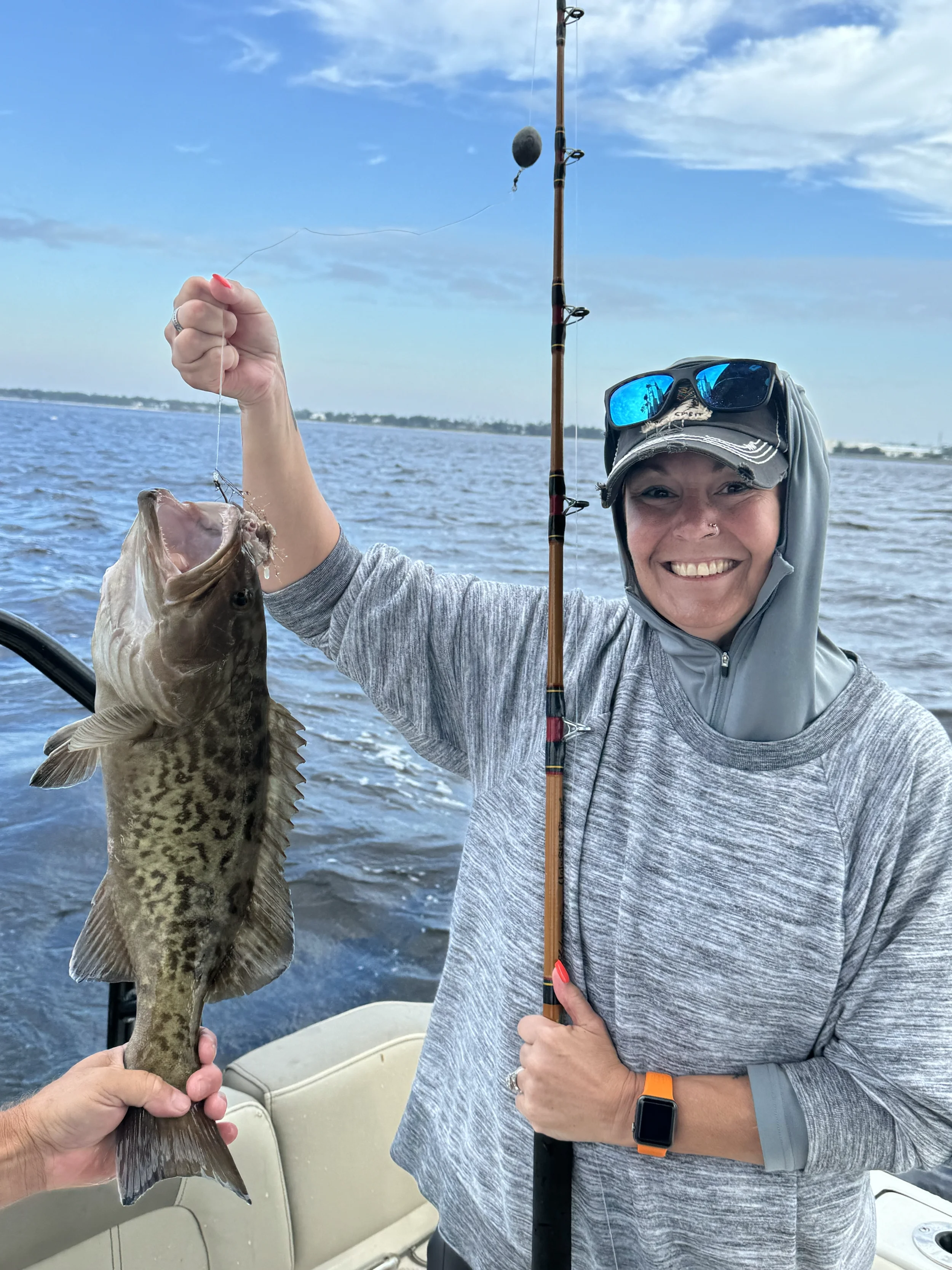 A woman is holding up a grouper she caught in the Gulf