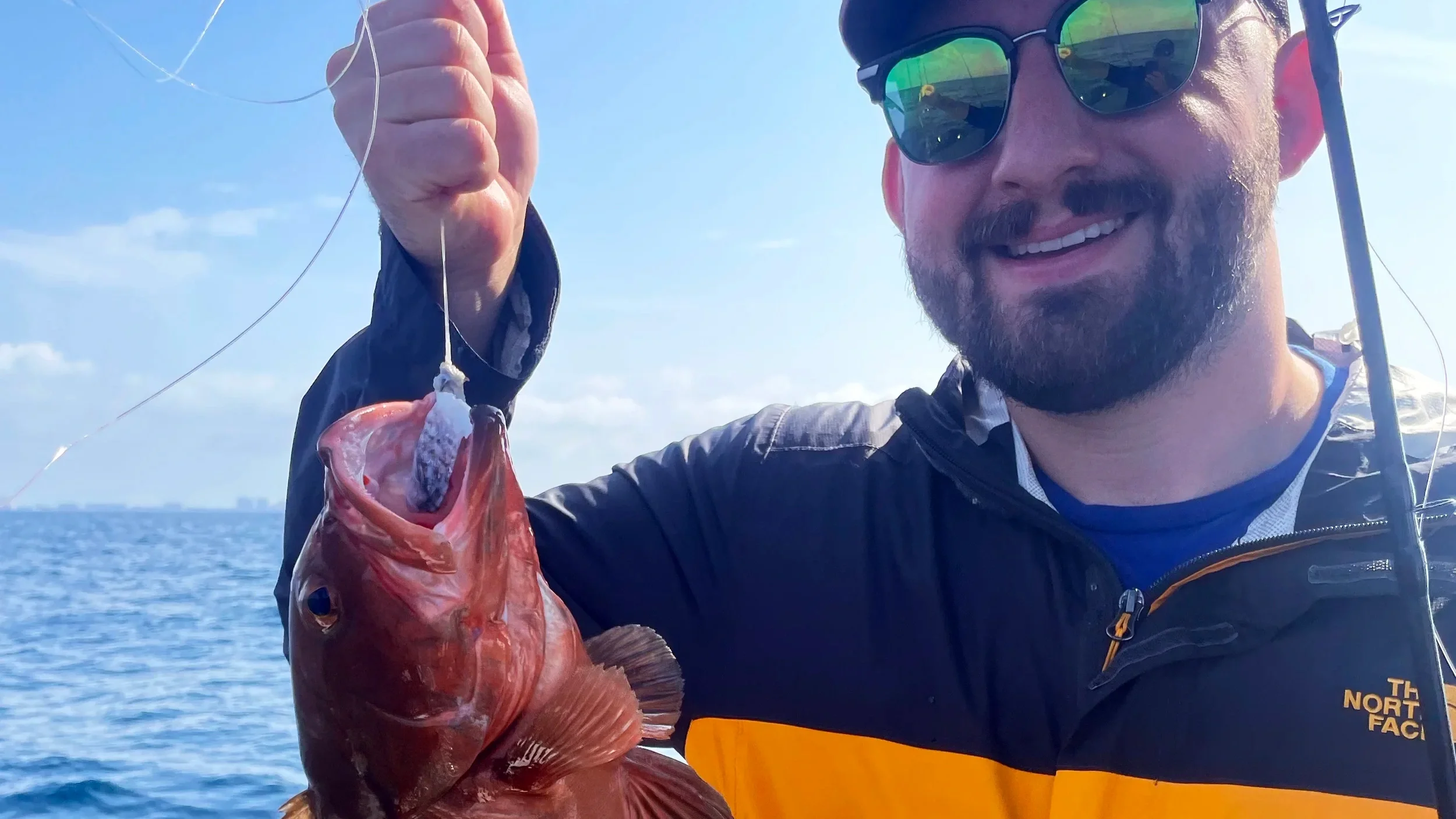 Man holds up a grouper that he caught on Bluewater Charter along Florida's Emerald Coast