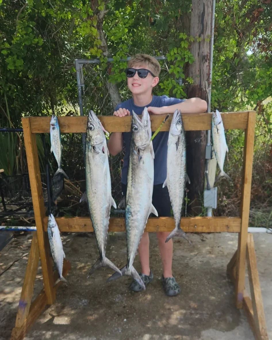 A boy stands behind fish he caught along the Emerald Coast in Florida
