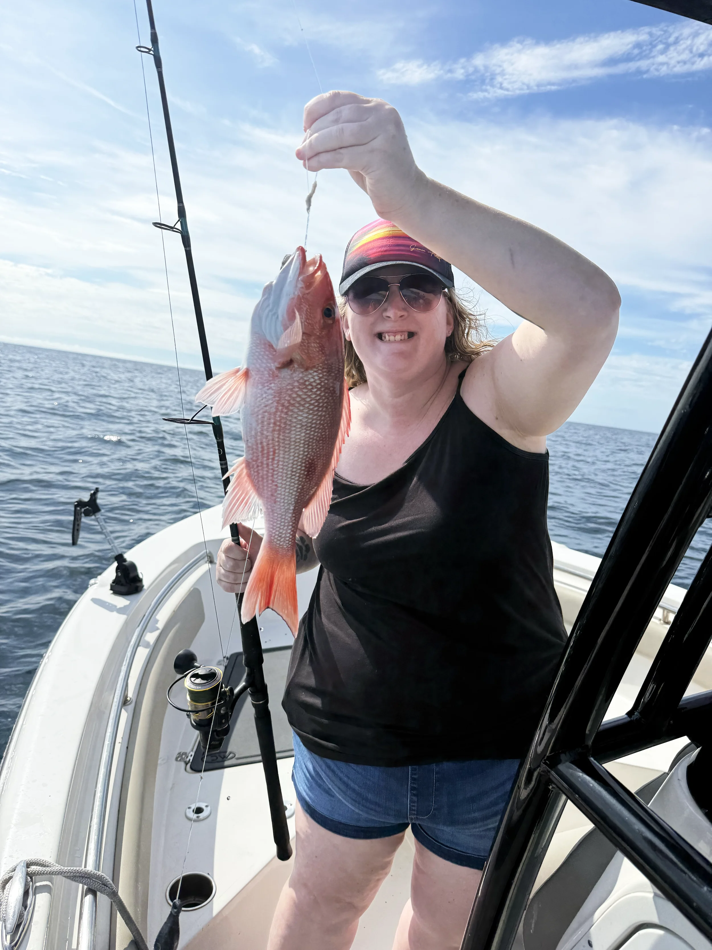 A woman holds up a vermilion snapper she caught along the Emerald Coast