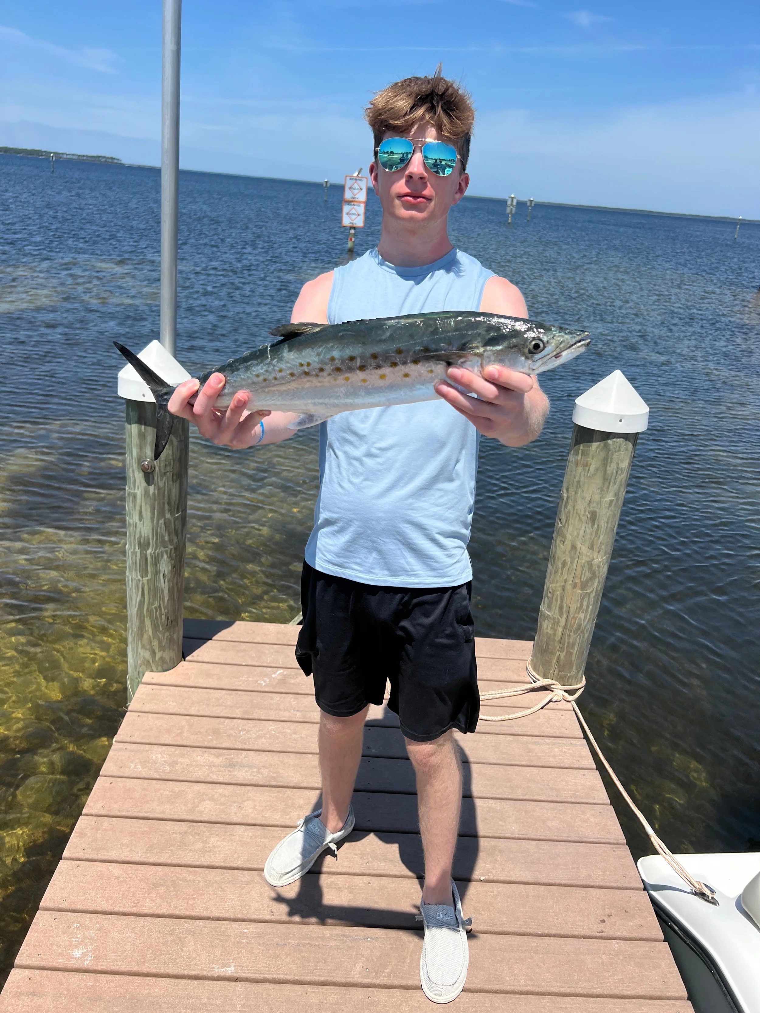Teen boy on dock holding Spanish Mackerel caught in the Gulf