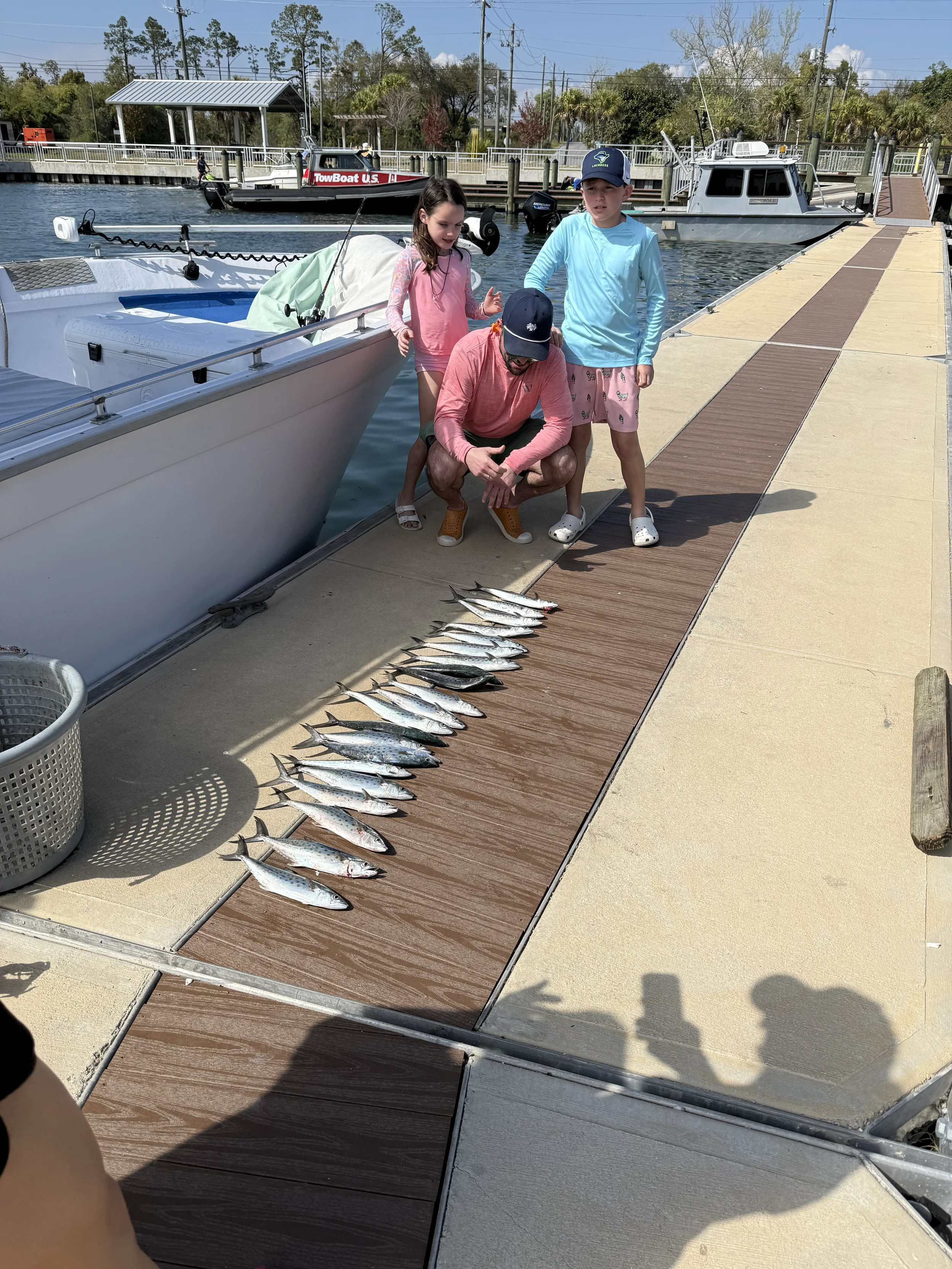 A man and his kids with their Gulf caught fish lined up on a dock