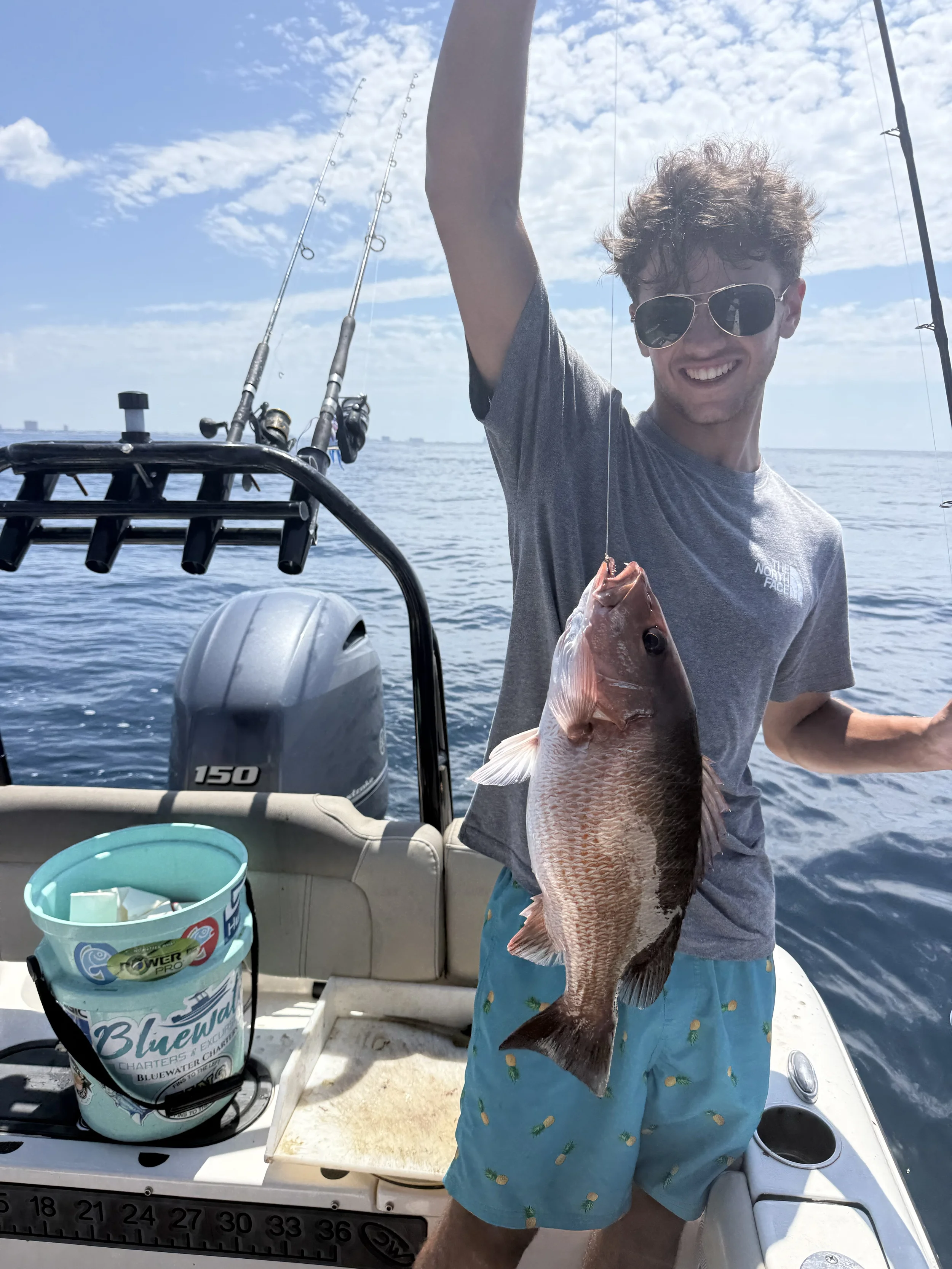Guest holding a mangrove snapper caught during an offshore fishing charter along Florida's Emerald Coast