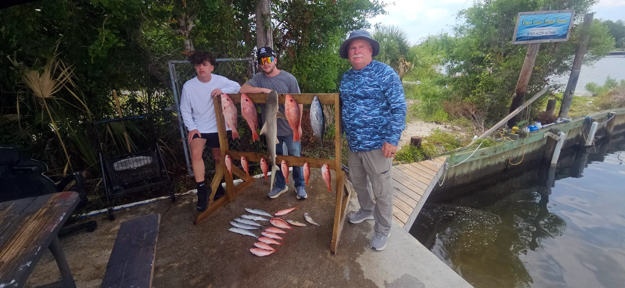 Man and teens on shore standing next to their Gulf fish