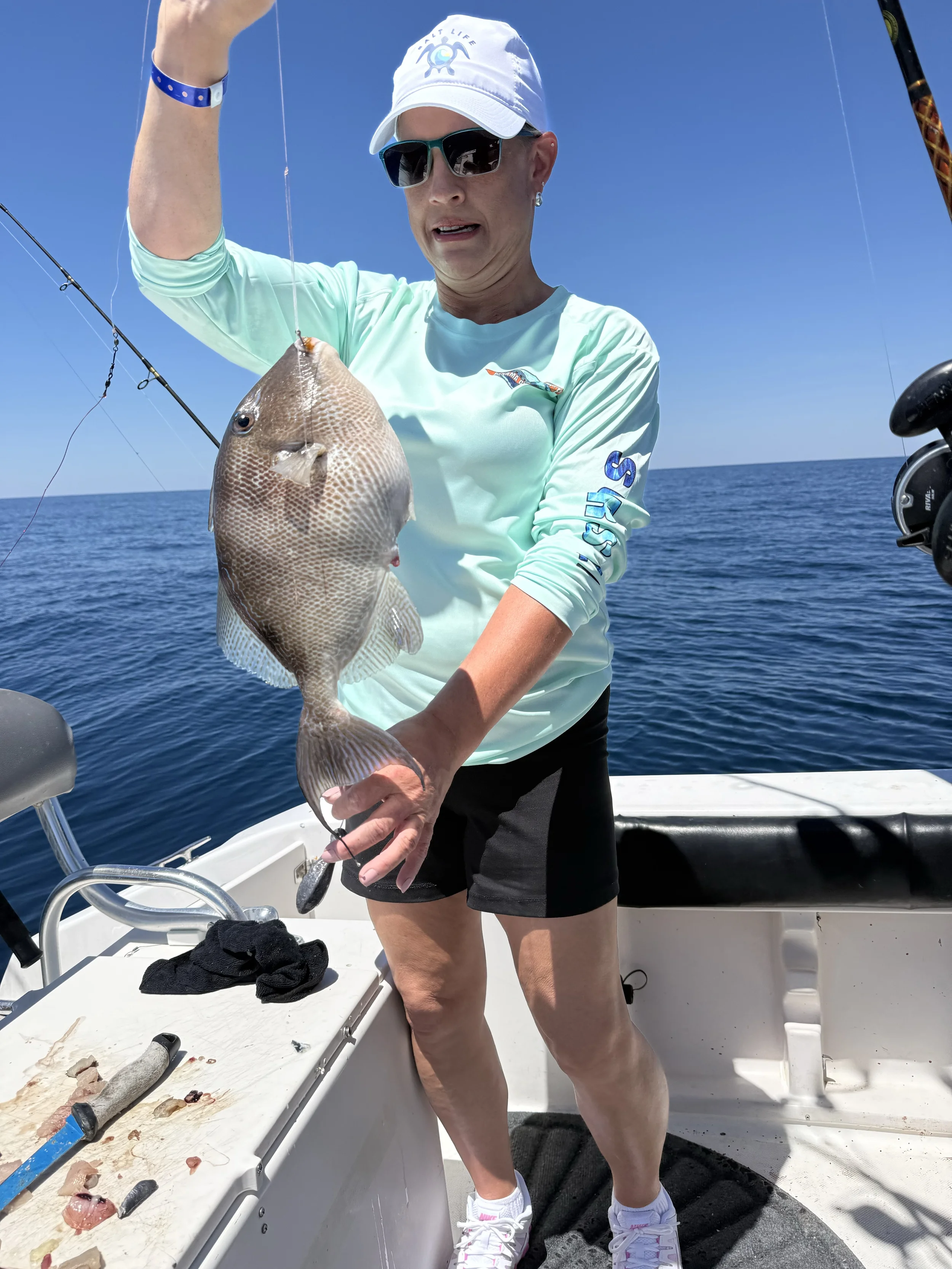 A woman holds up a large triggerfish she caught along the Emerald Coast