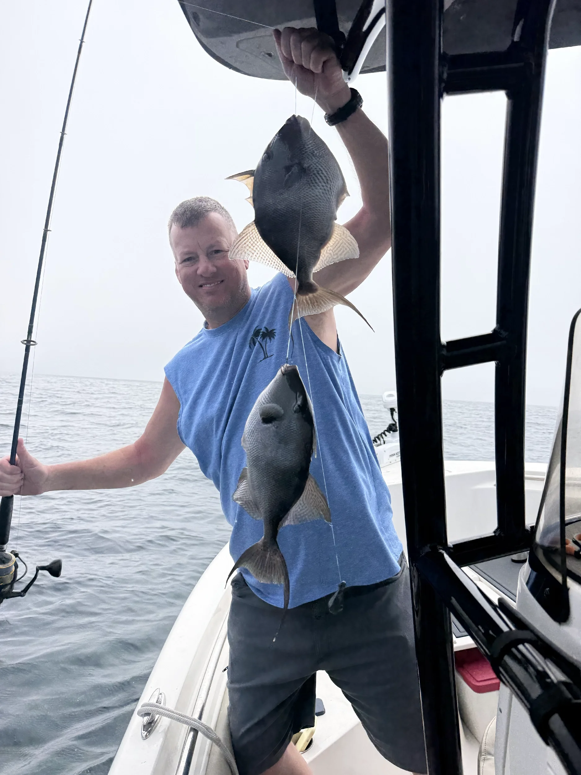 Man holding up his Triggerfish on a boat in the Gulf