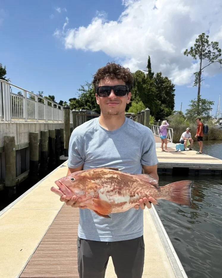 A young man holds a red snapper caught during an offshore fishing charter near Panama City Beach and 30A