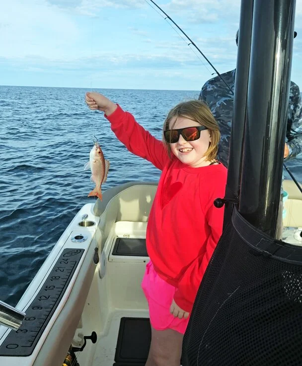 A young girl holds up a vermilion snapper along the Gulf Coast