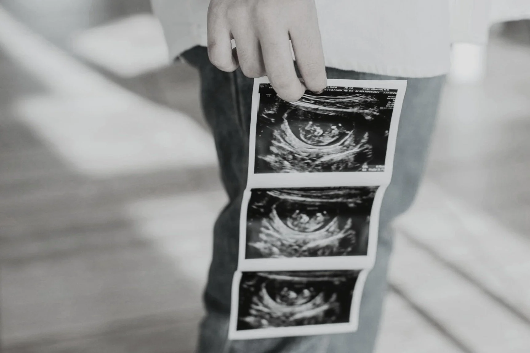 Person holding ultrasound images of a developing fetus.