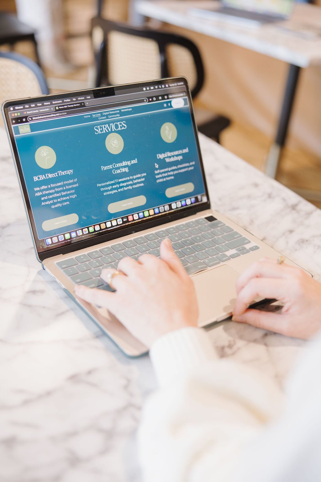 Person using a laptop at a marble table, browsing a webpage offering counseling and therapy services.