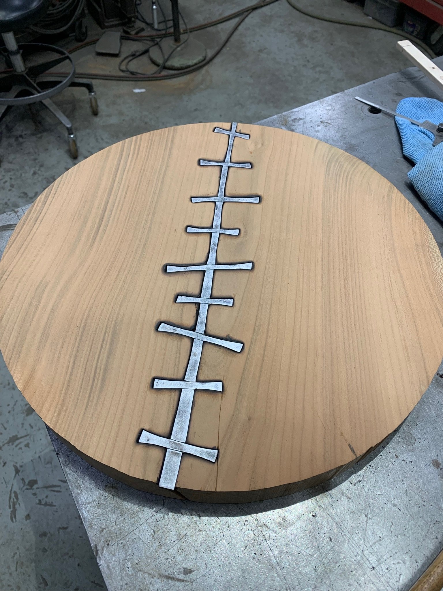 Round wooden table with a metal cross-shaped design inlaid in the center.