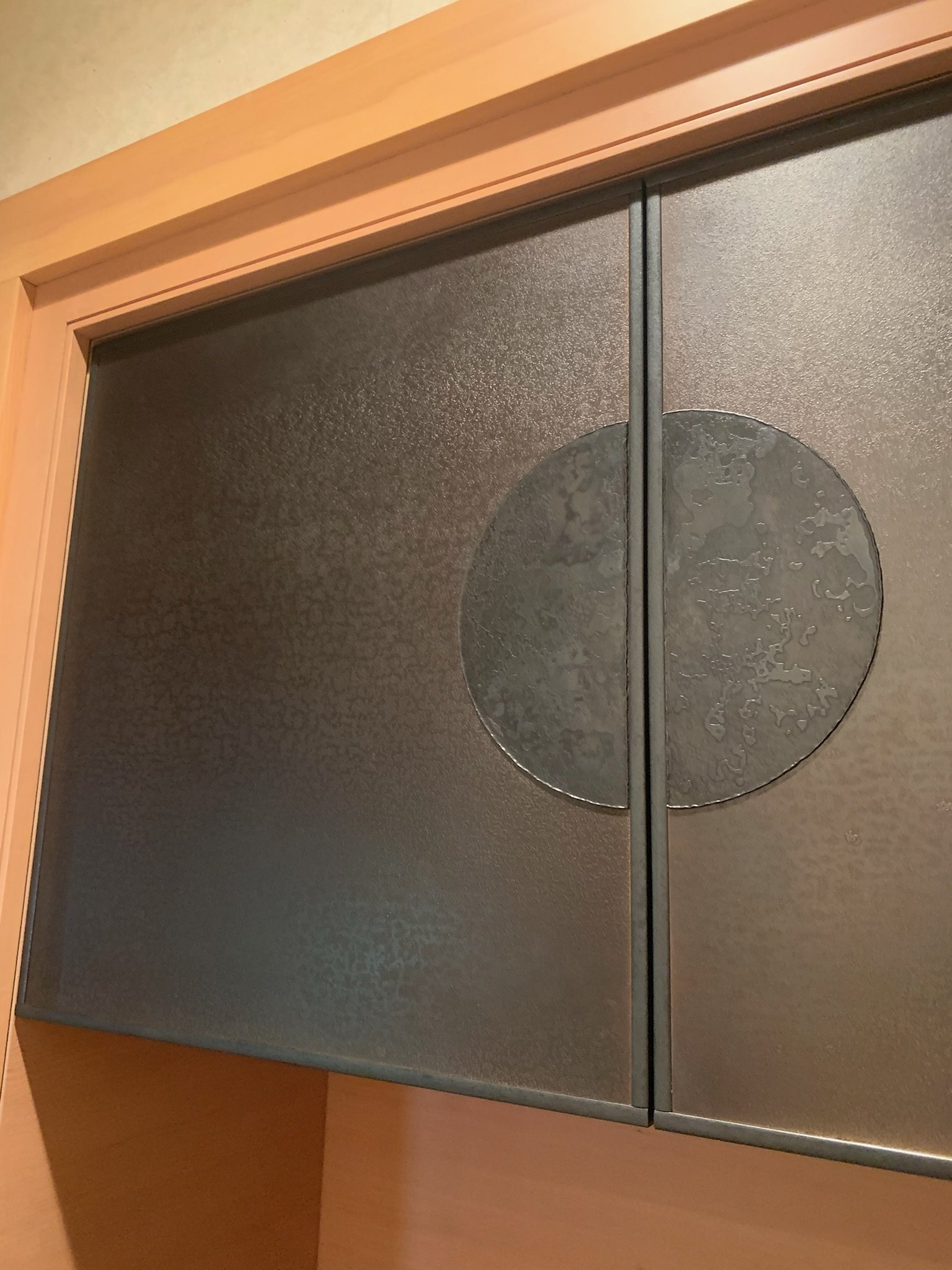 A black metal cabinet with a textured surface and a large circular design in the center.