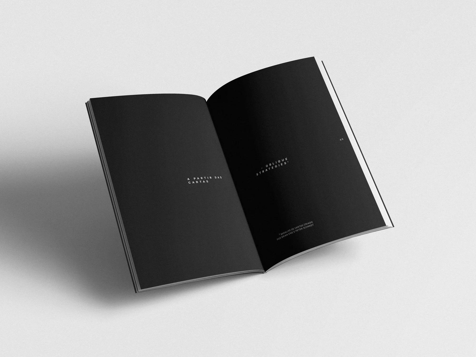 Livro aberto com páginas pretas e texto em português na página esquerda e direita, em um fundo branco