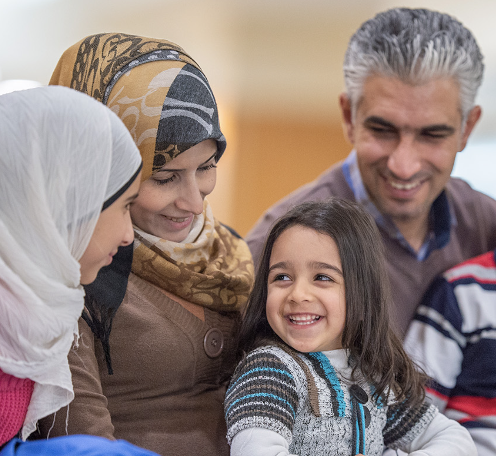 A refugee family smiling together: two women, a man, and a young girl