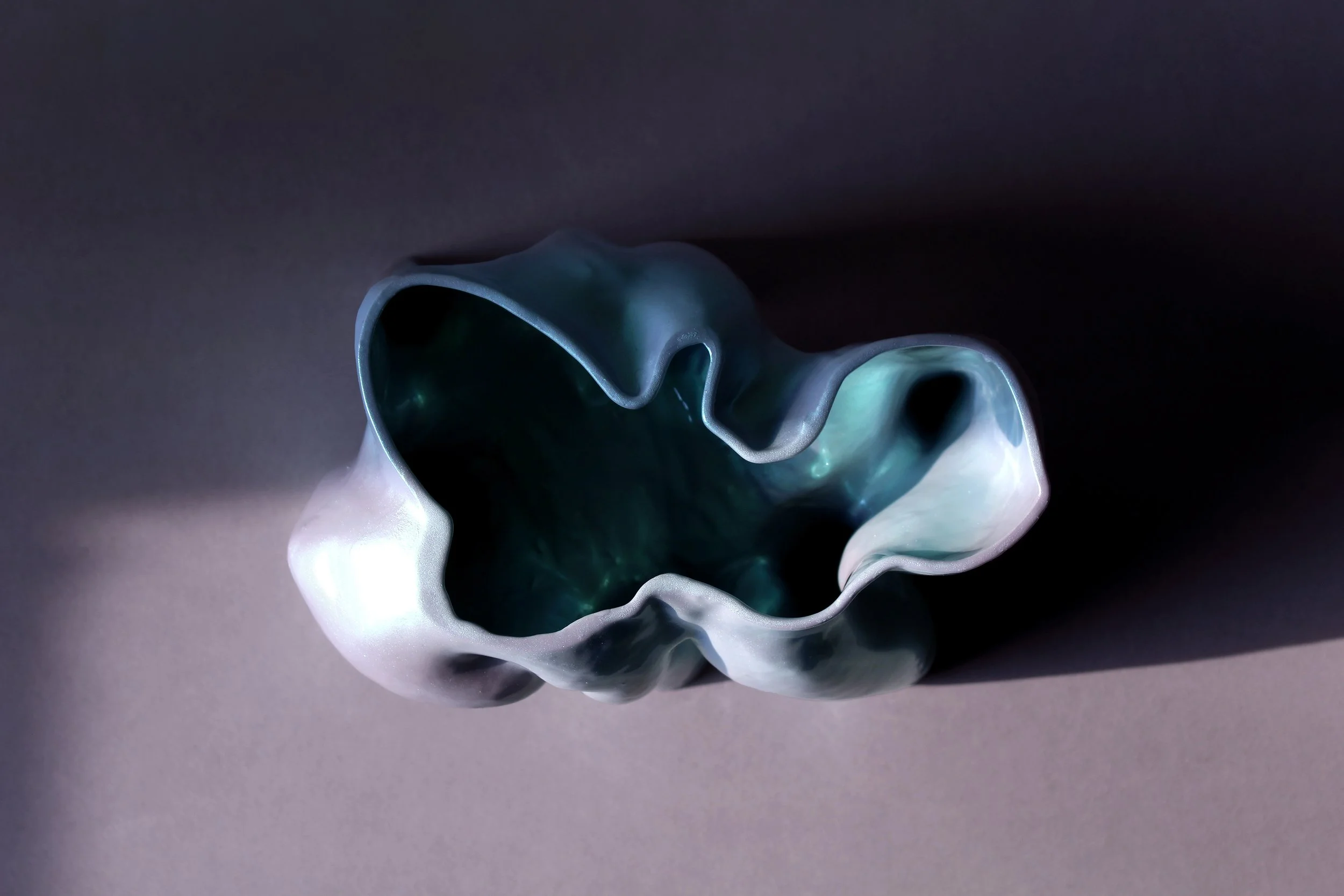 Overhead view of organically contoured vessel with irregular rim and glowing teal interior; tactile and biomorphic home object from Pet Objects 1
