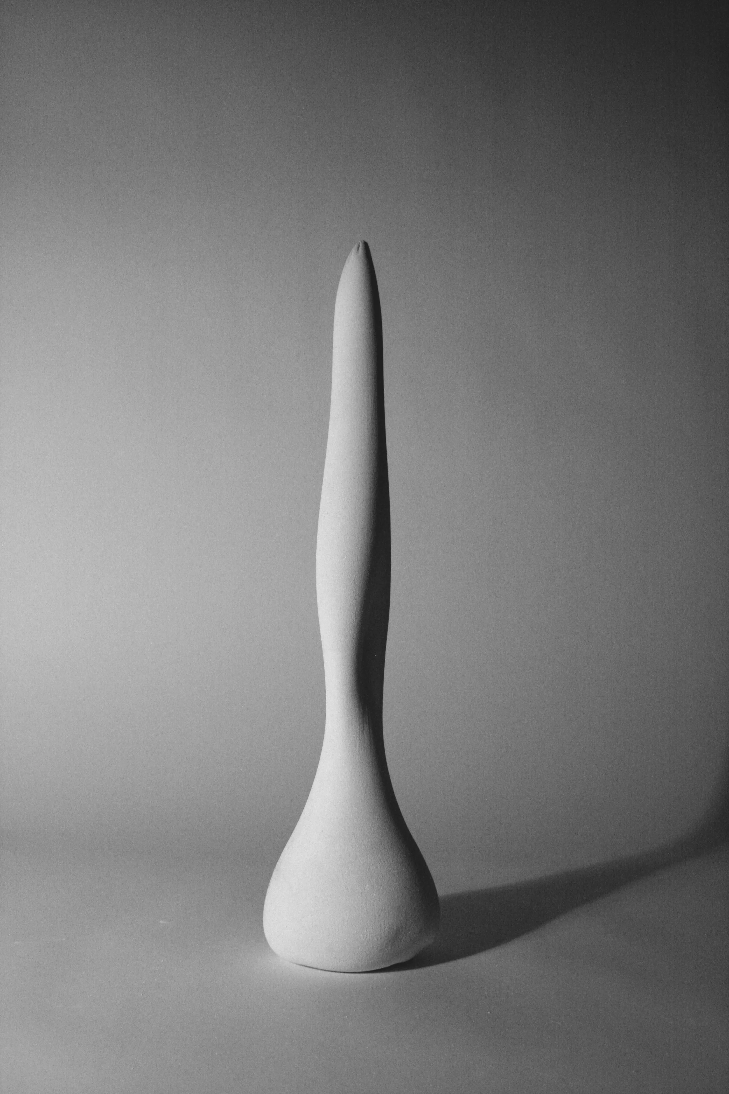 A tall vertical sculptural column cast in plaster using fabric formwork with gentle curves and shadows