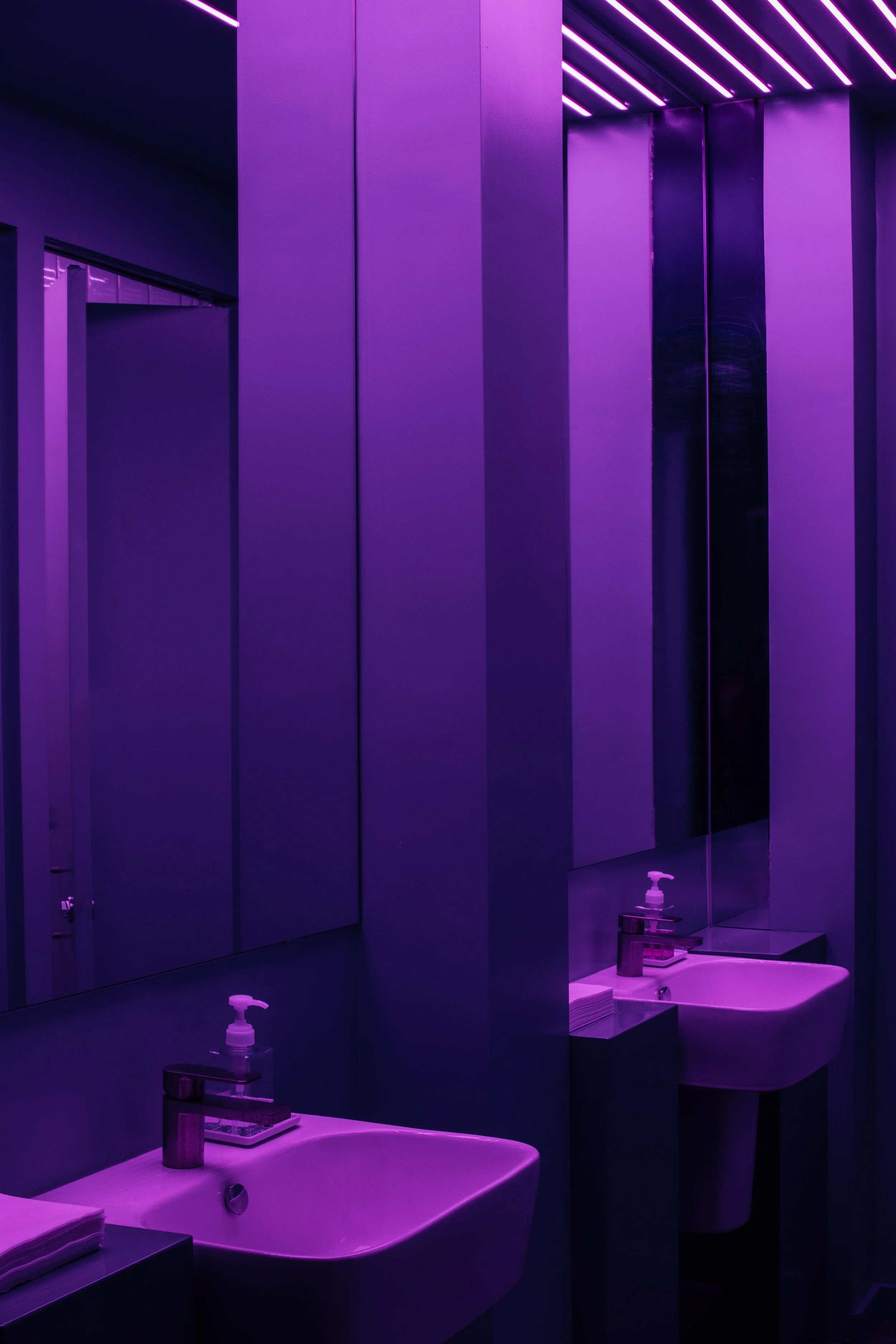 Washrooms with purple walls and linear LED light fixtures