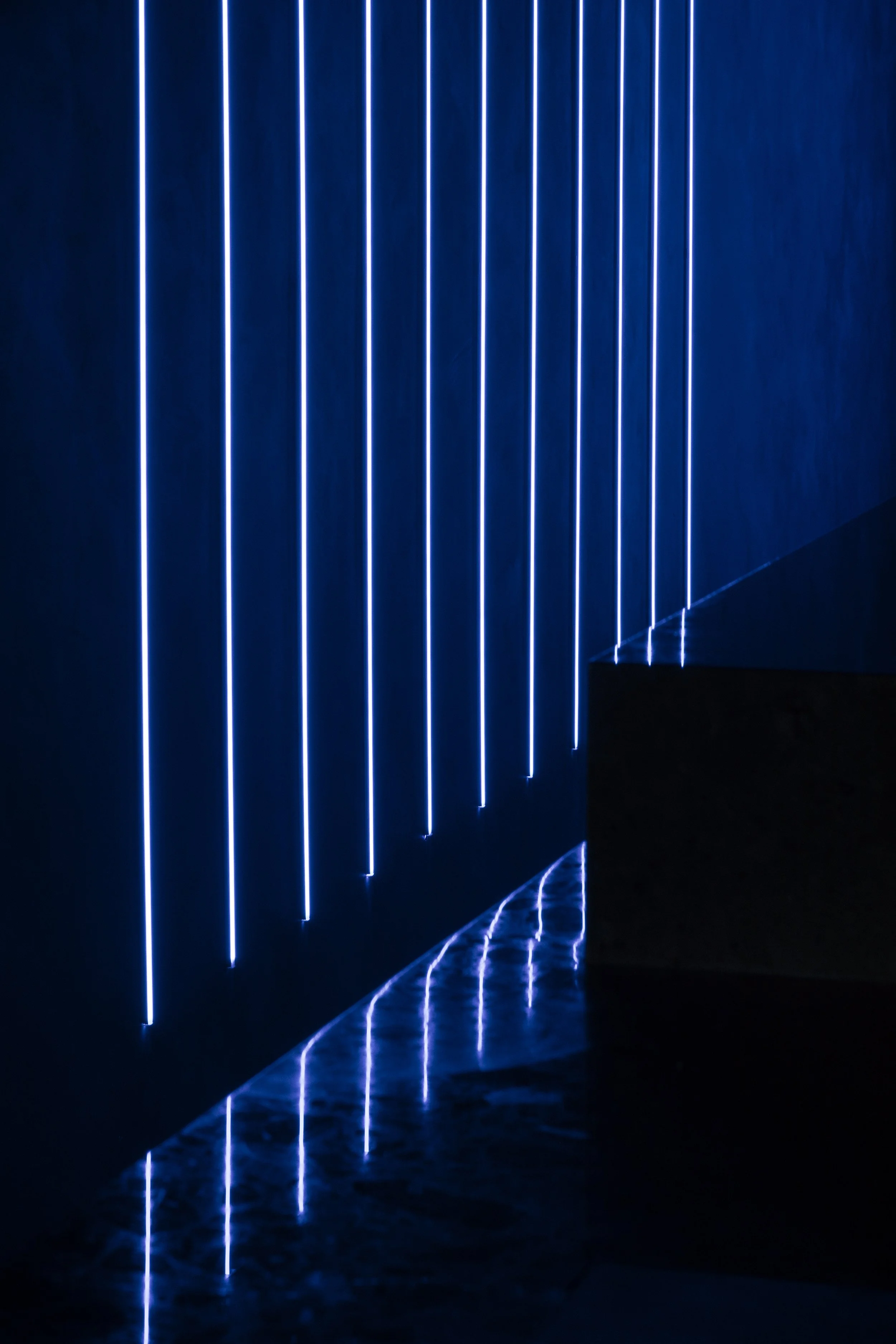 Detail of linear LED light fixtures reflecting on stone surface