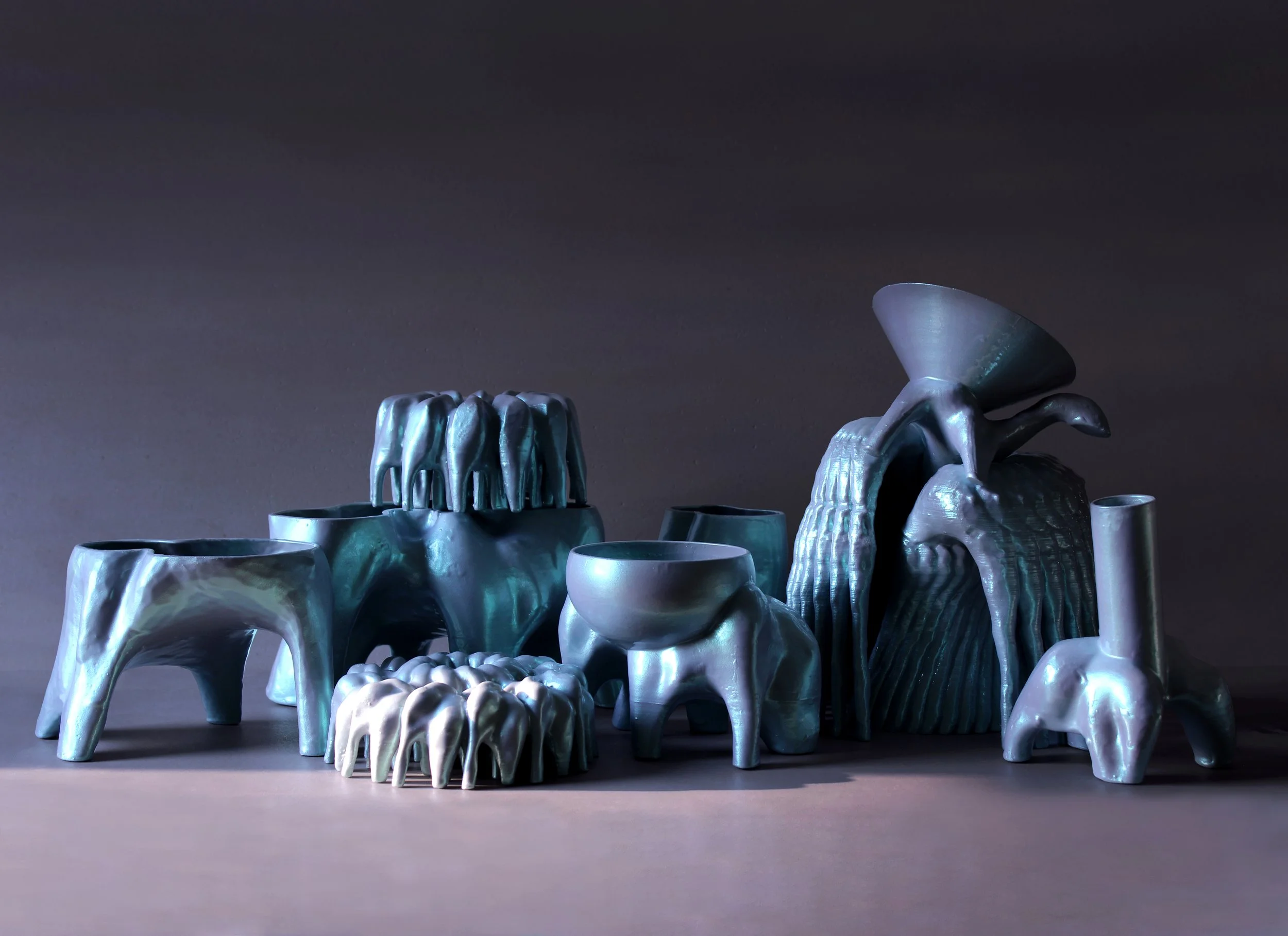 Collection of iridescent 3D-printed sculptural vessels from the Pet Objects series, featuring abstract, animal-like forms and a pearlescent finish.