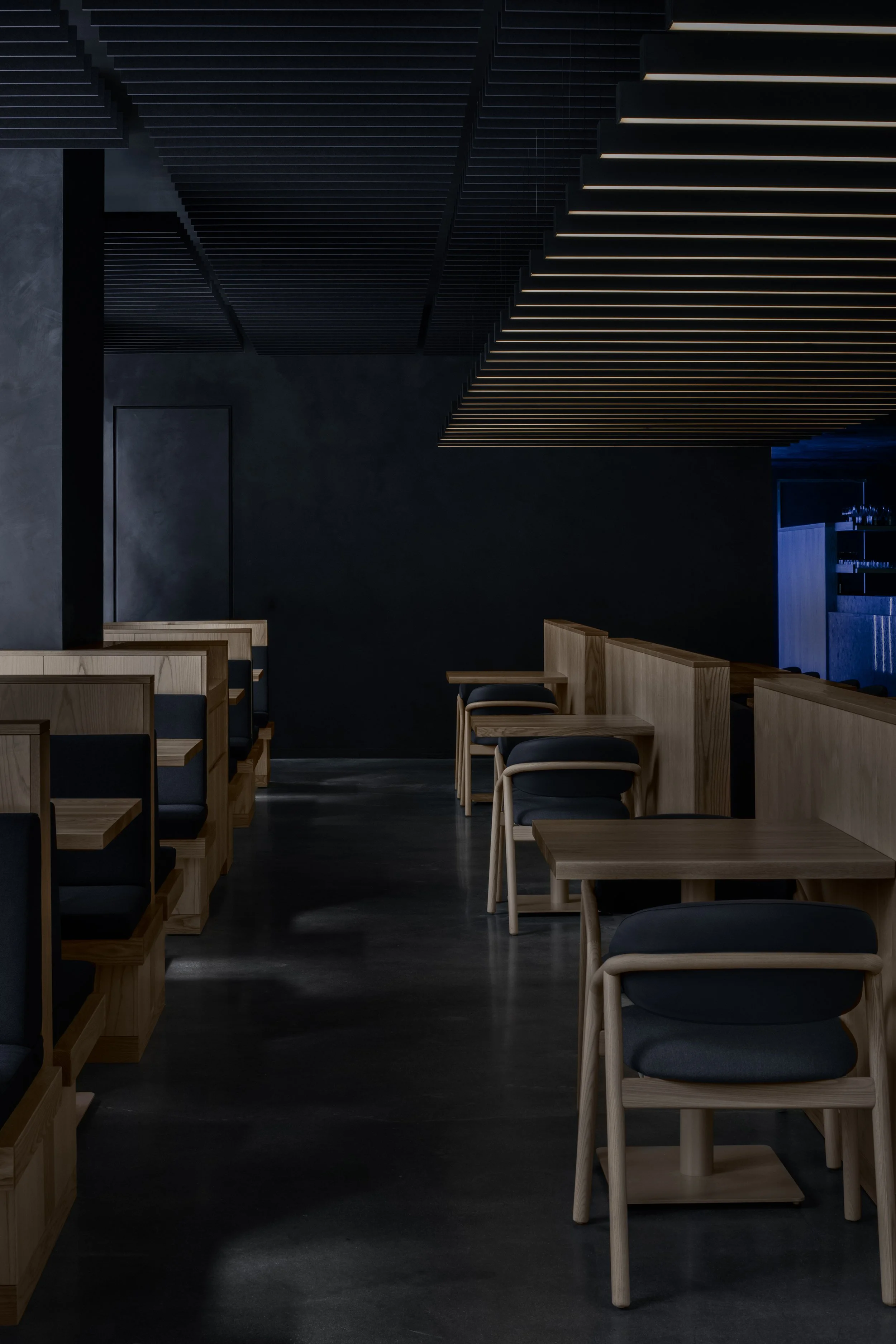 Minimalist Japanese restaurant with blue limewash walls and wood banquettes
